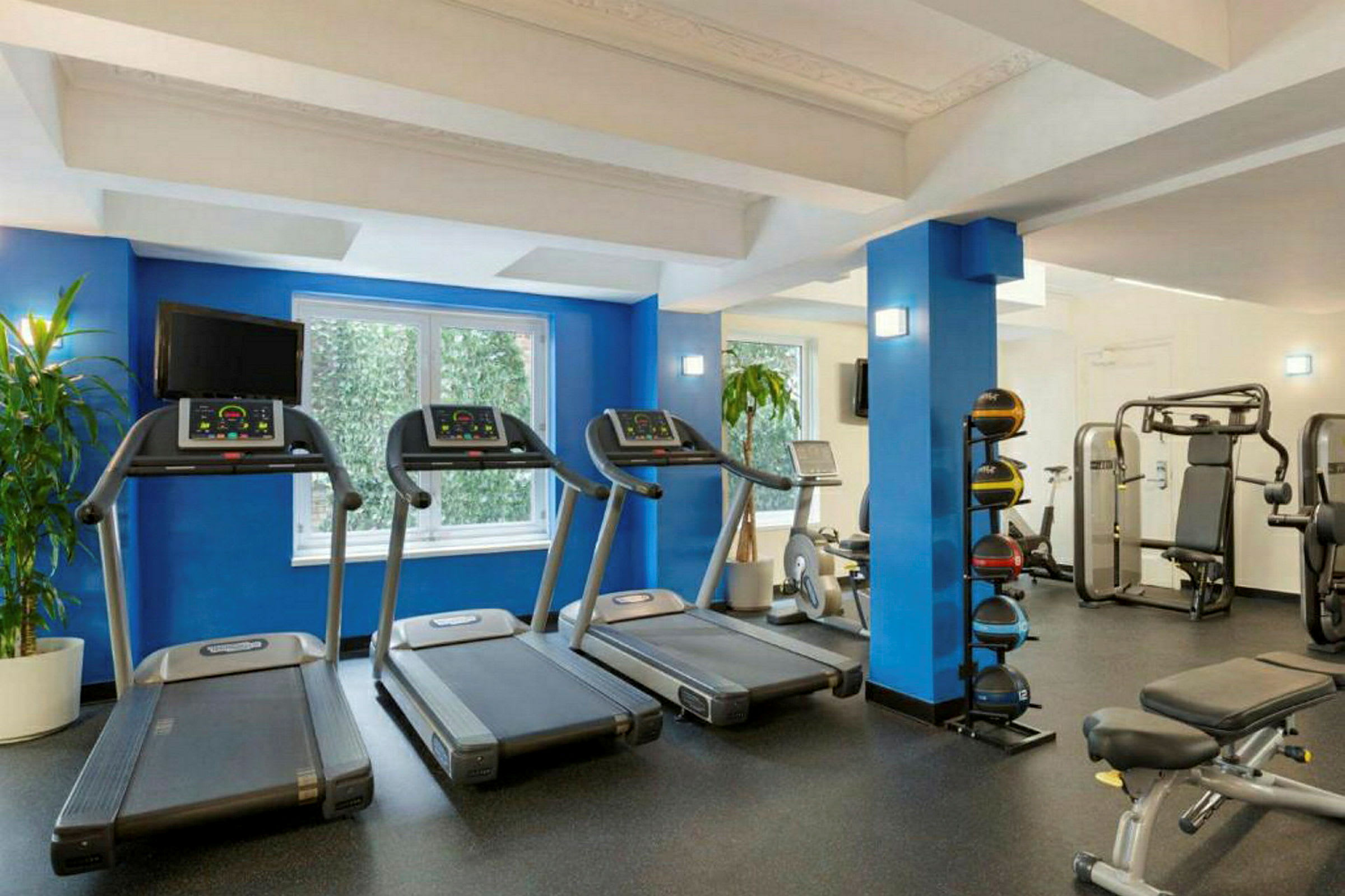 Bild av ett ljust gym med olika träningsmaskiner såsom löpband och träningsbänk. (AI-genererad text)