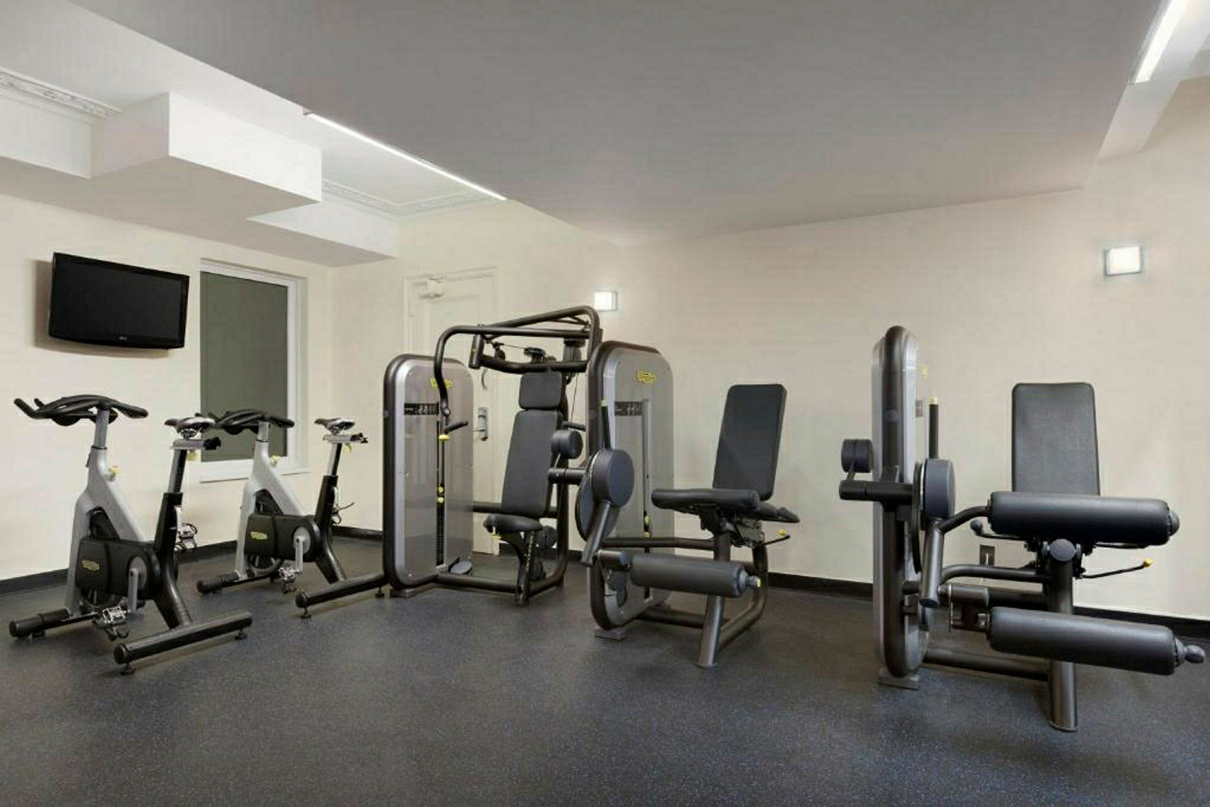 Bild av ett gym med träningsmaskiner, inklusive motionscyklar och styrketräningsutrustning. (AI-genererad text)