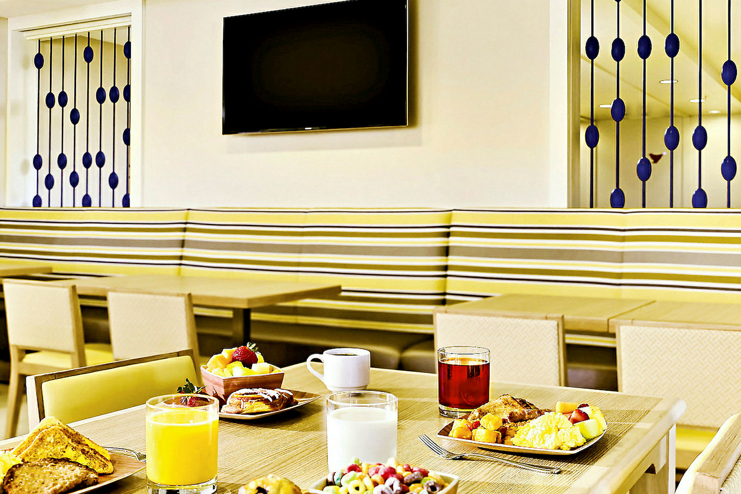 Ett dukat frukostbord med olika drycker och måltider i en modern matsal. (AI-genererad text)