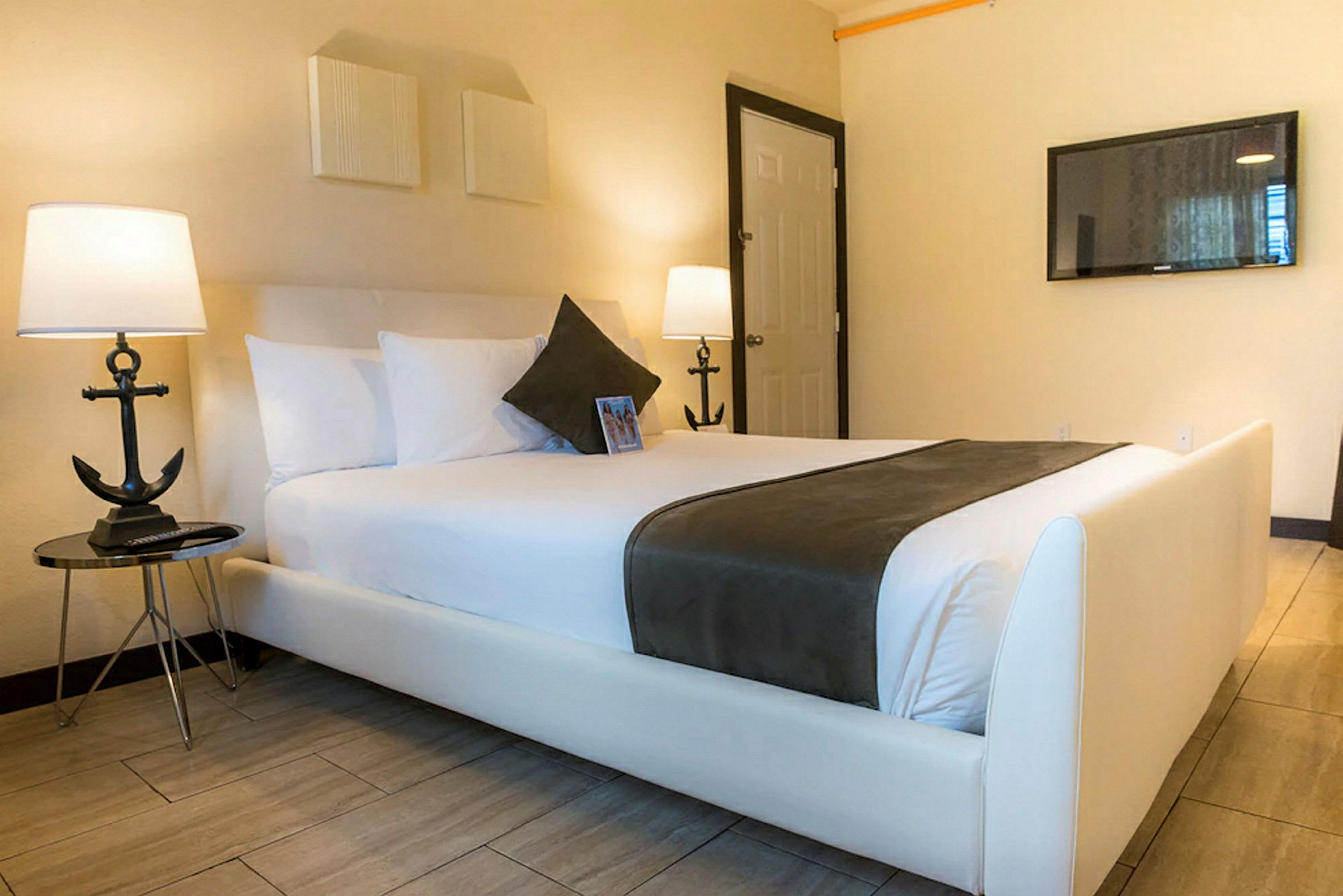 Bild av ett hotellrum med en bäddad säng utrustad med vita sängkläder och grått överkast. (AI-genererad text)