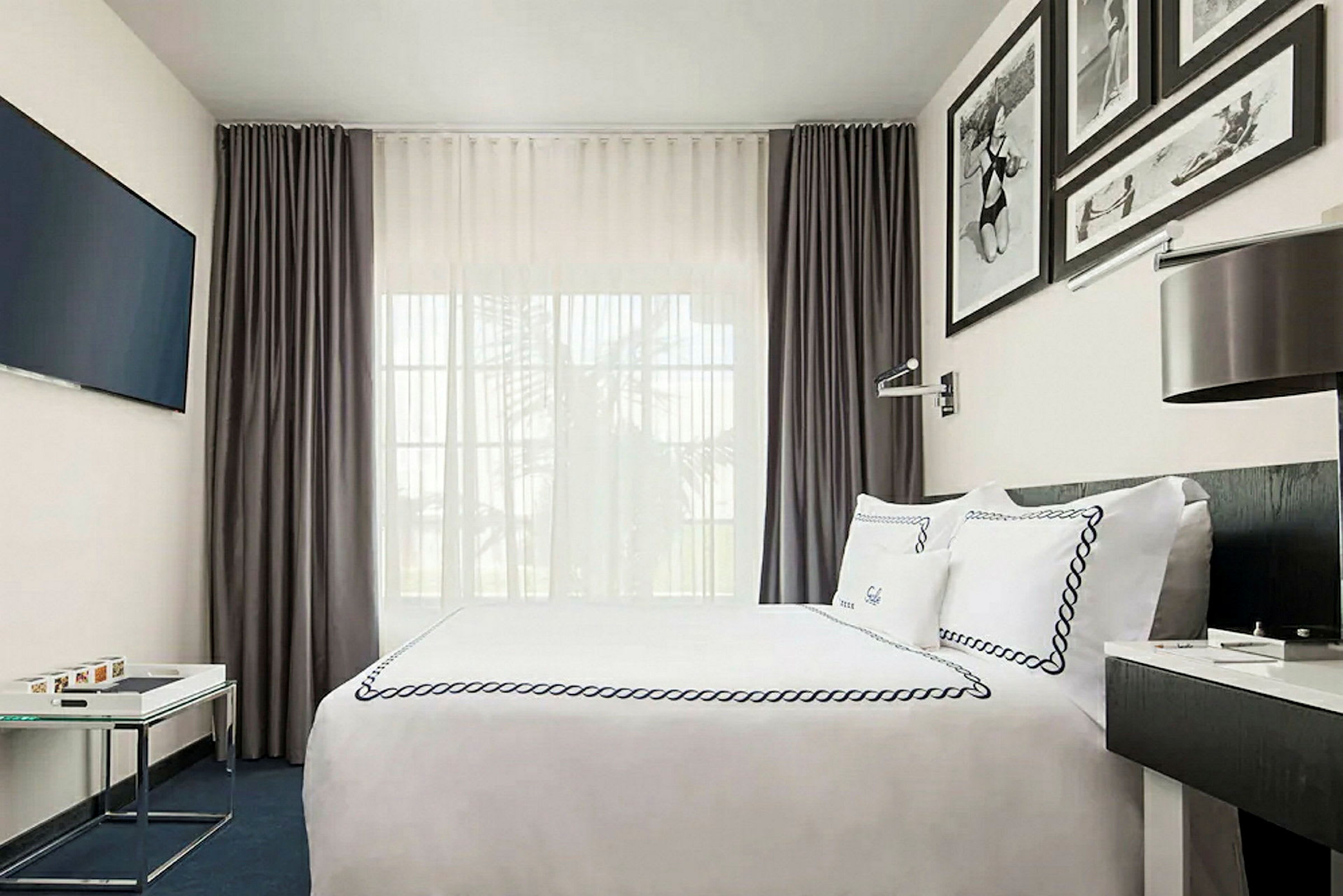 Modernt möblerat hotellrum med säng, väggdekorationer och gardiner. (AI-genererad text)
