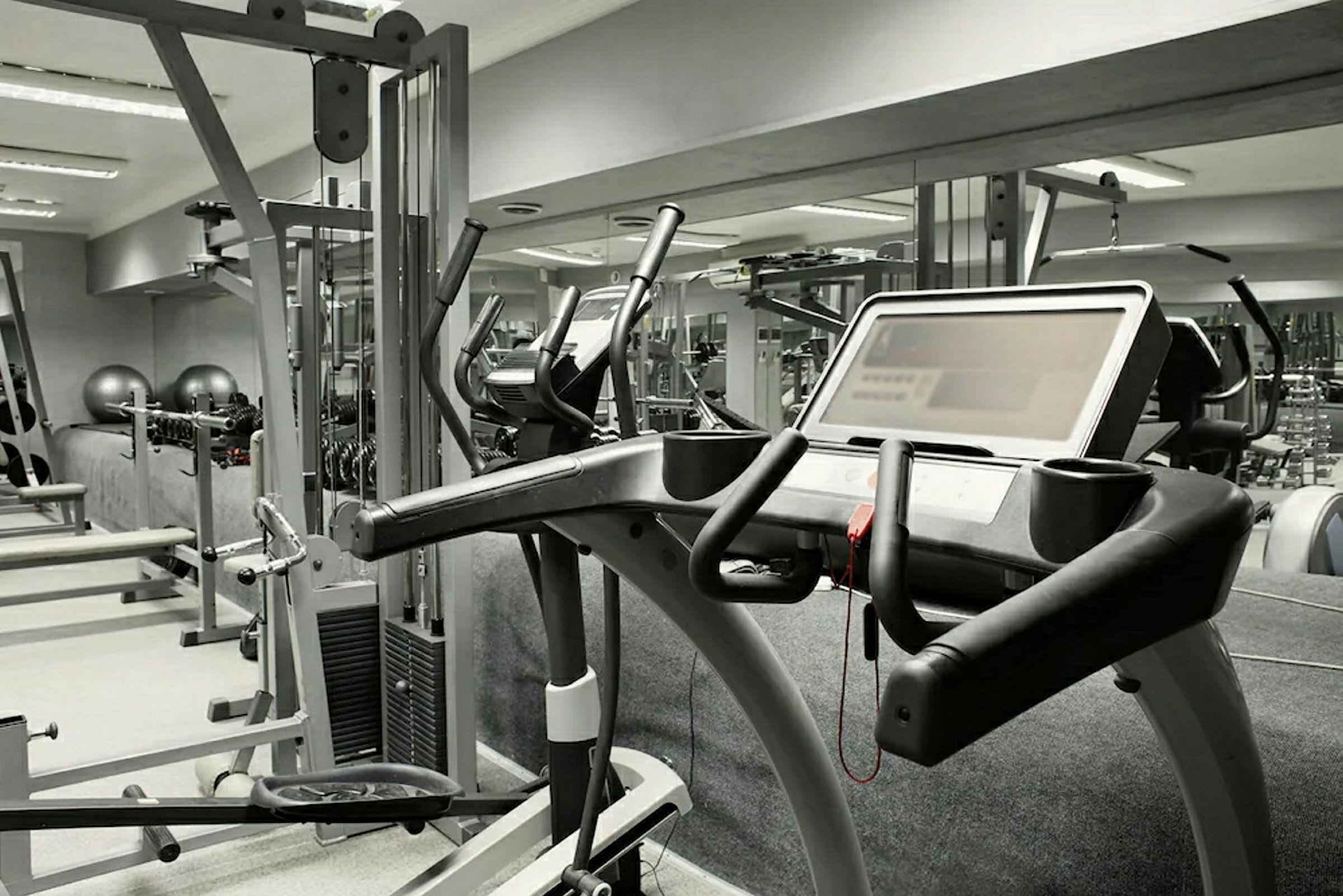 Ett gym med olika träningsmaskiner, inklusive ett löpband i förgrunden. (AI-genererad text)