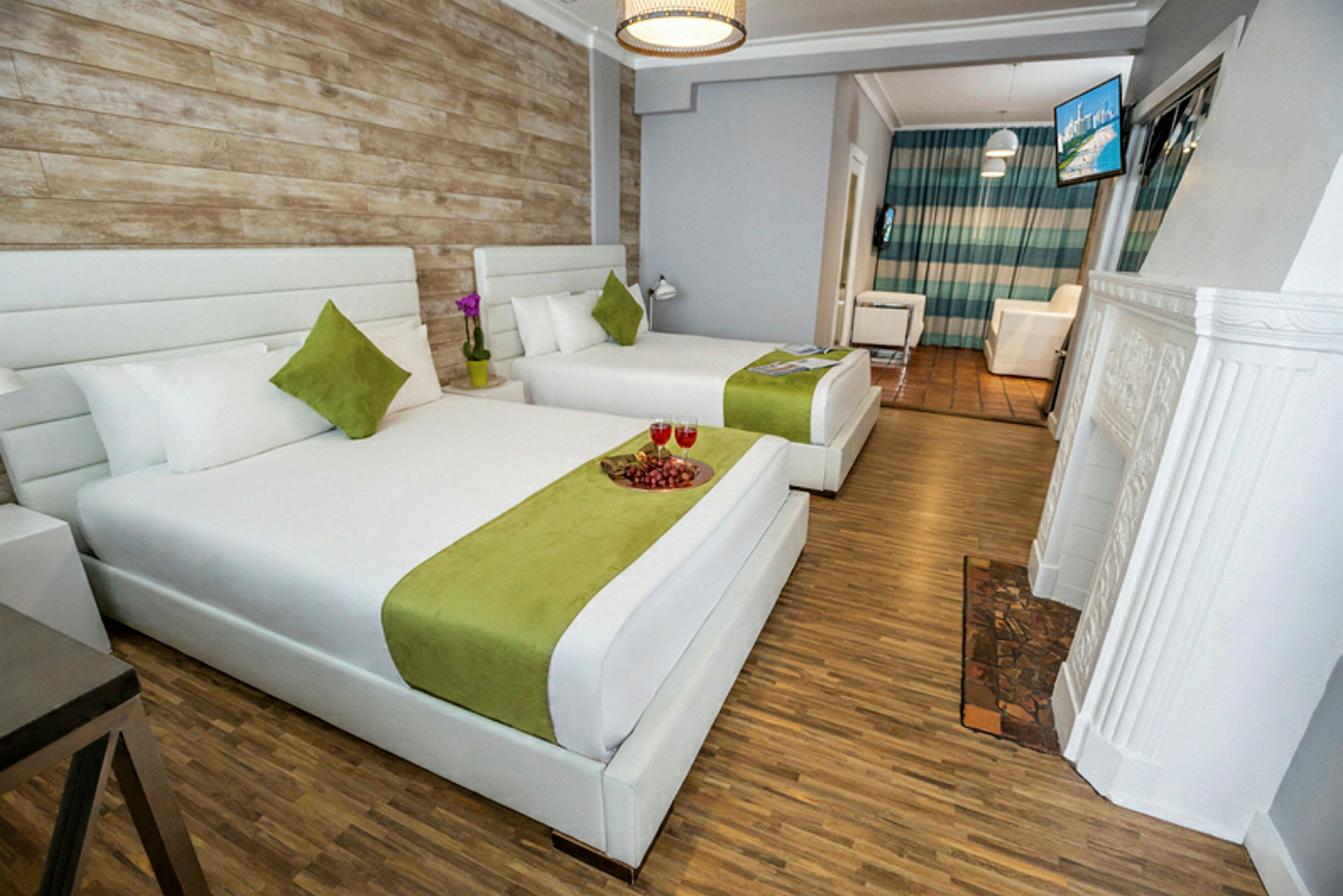 Hotellrum med två stora sängar klädda i vit och grön bäddning, ett träfärgat golv och en vägg i rustik stil. (AI-genererad text)