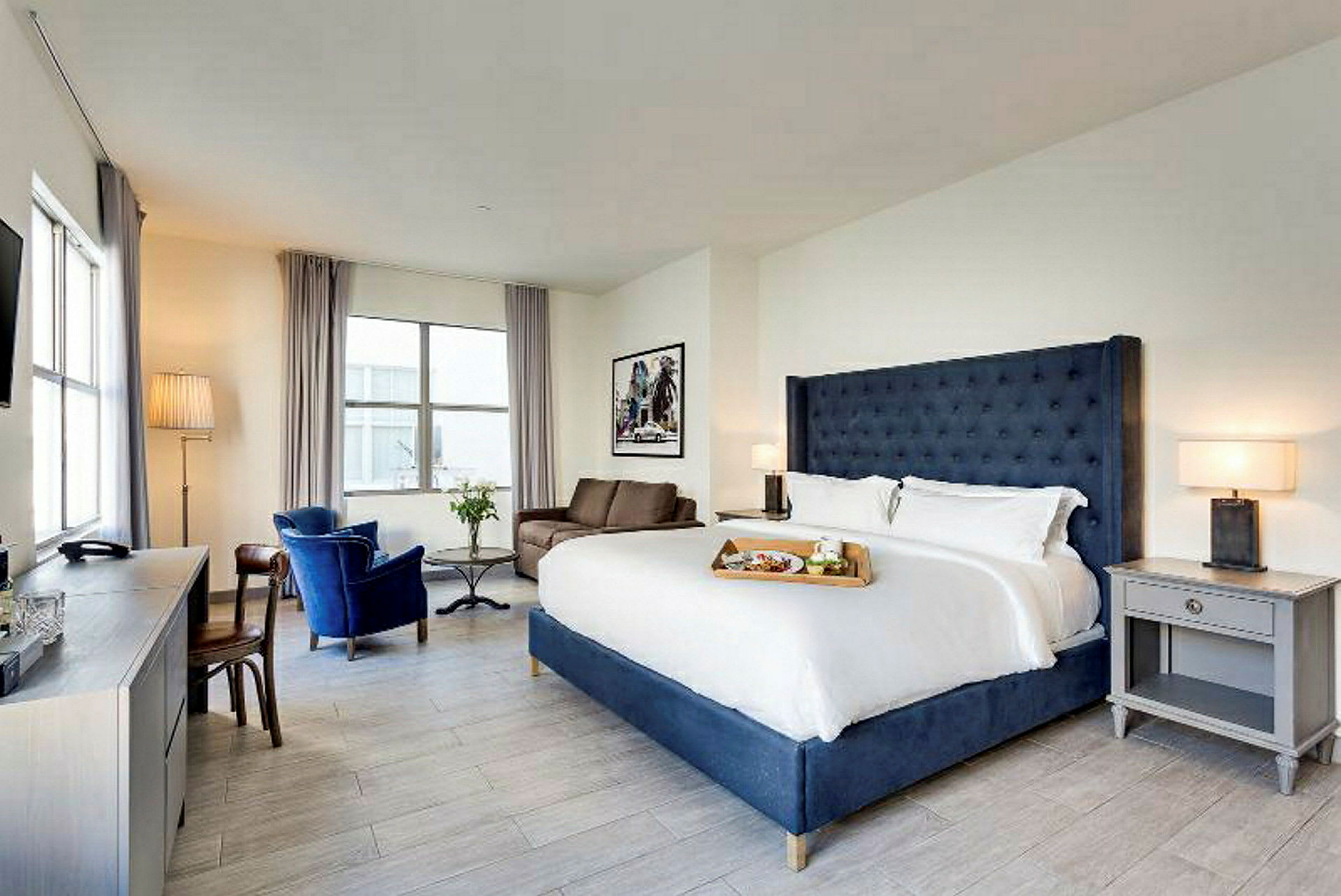 Ett ljust hotellrum med stor dubbelsäng, fåtöljer och ett skrivbord. (AI-genererad text)