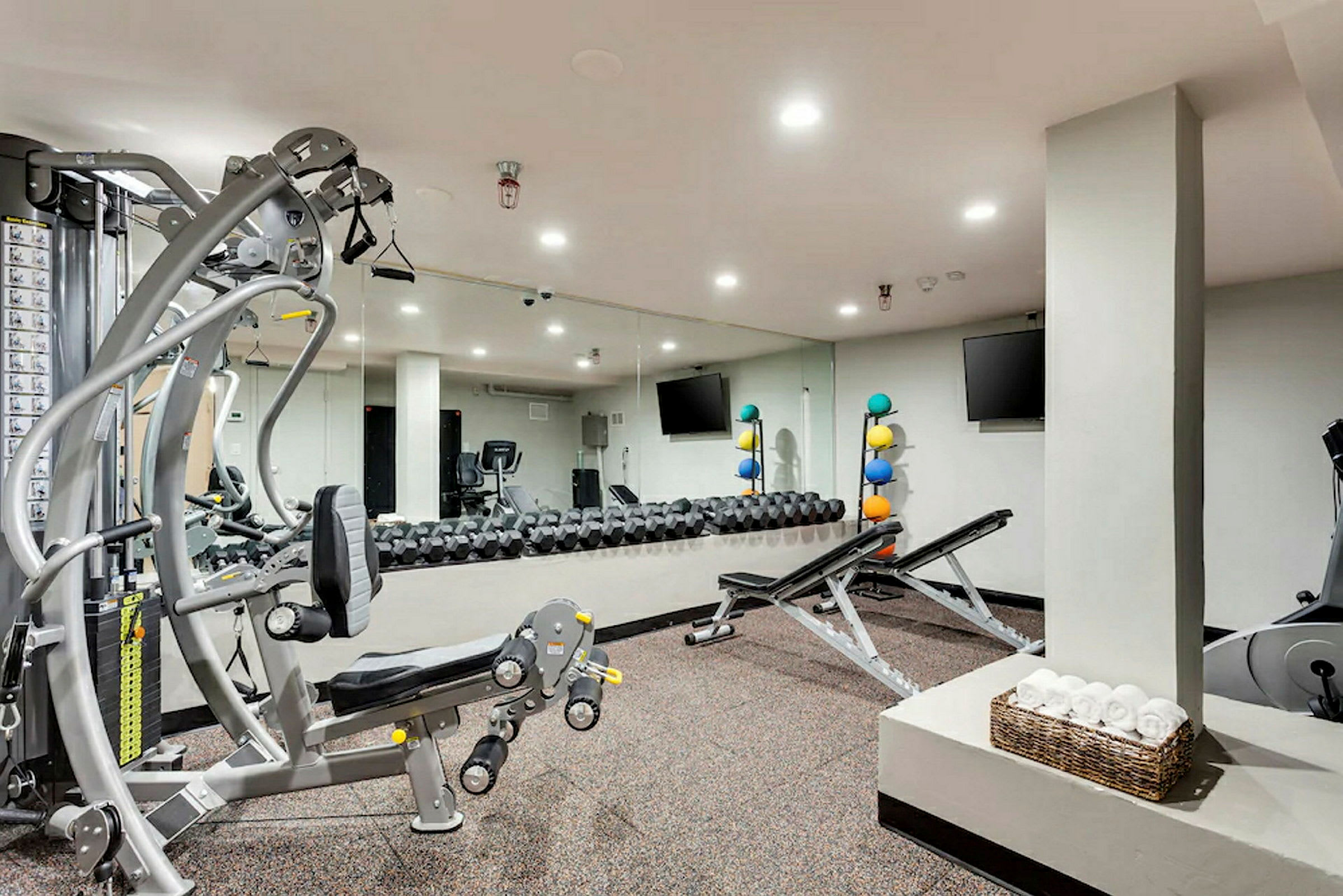 Ett gym med träningsutrustning och spegelvägg. (AI-genererad text)