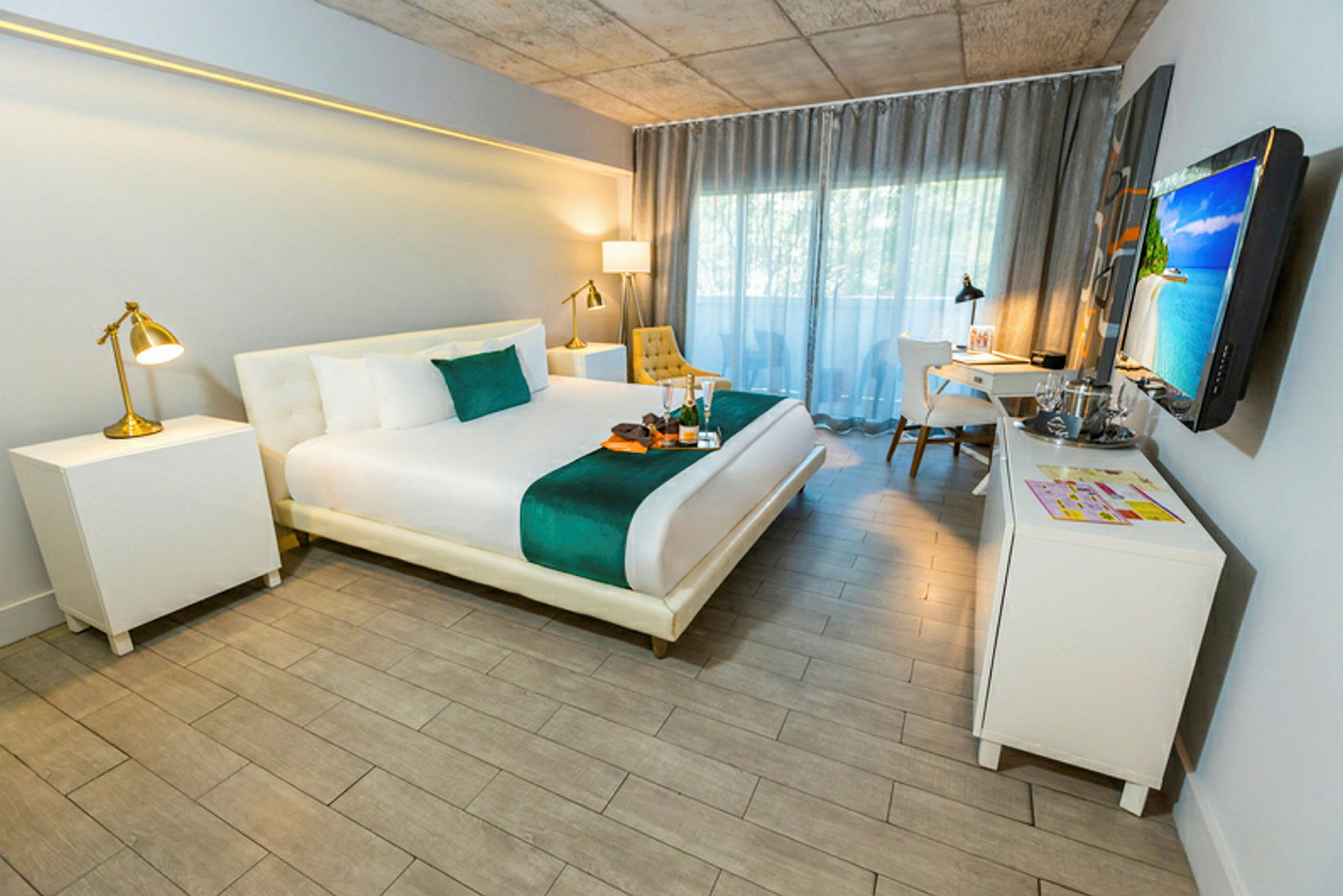 Ett modernt hotellrum med en dubbelsäng, nattduksbord, skrivbord, och ett fönster med gardiner. (AI-genererad text)