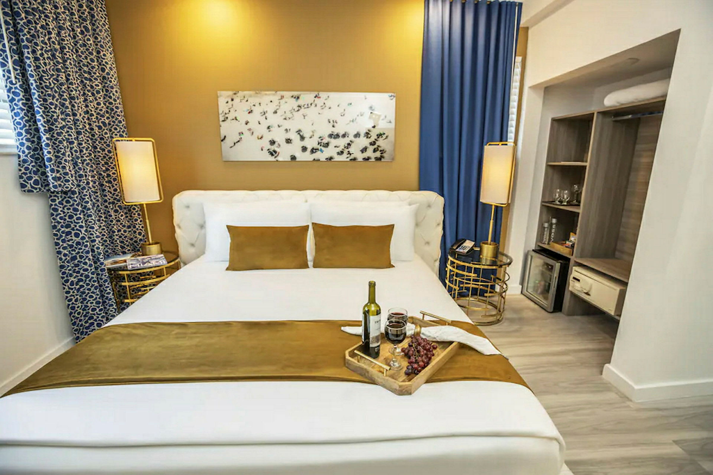 Ett hotellrum med en stor säng bäddad med vita och guldbruna textilier. Detaljer inkluderar nattduksbord och dekorationer. (AI-genererad text)