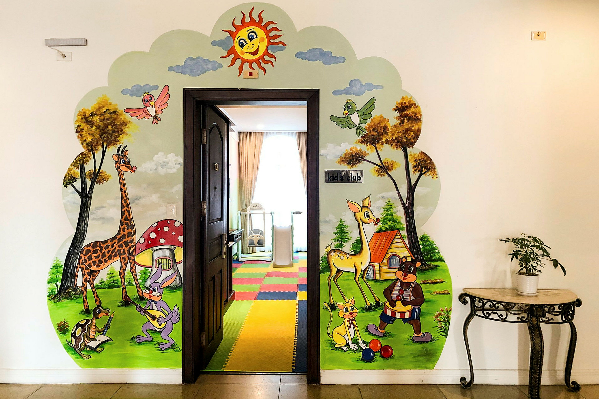 En dörr omgiven av en färgglad väggmålning med djur och naturmotiv, inklusive en giraff, en fågel och andra illustrerade karaktärer nära dörrens sidor. (AI-genererad text)