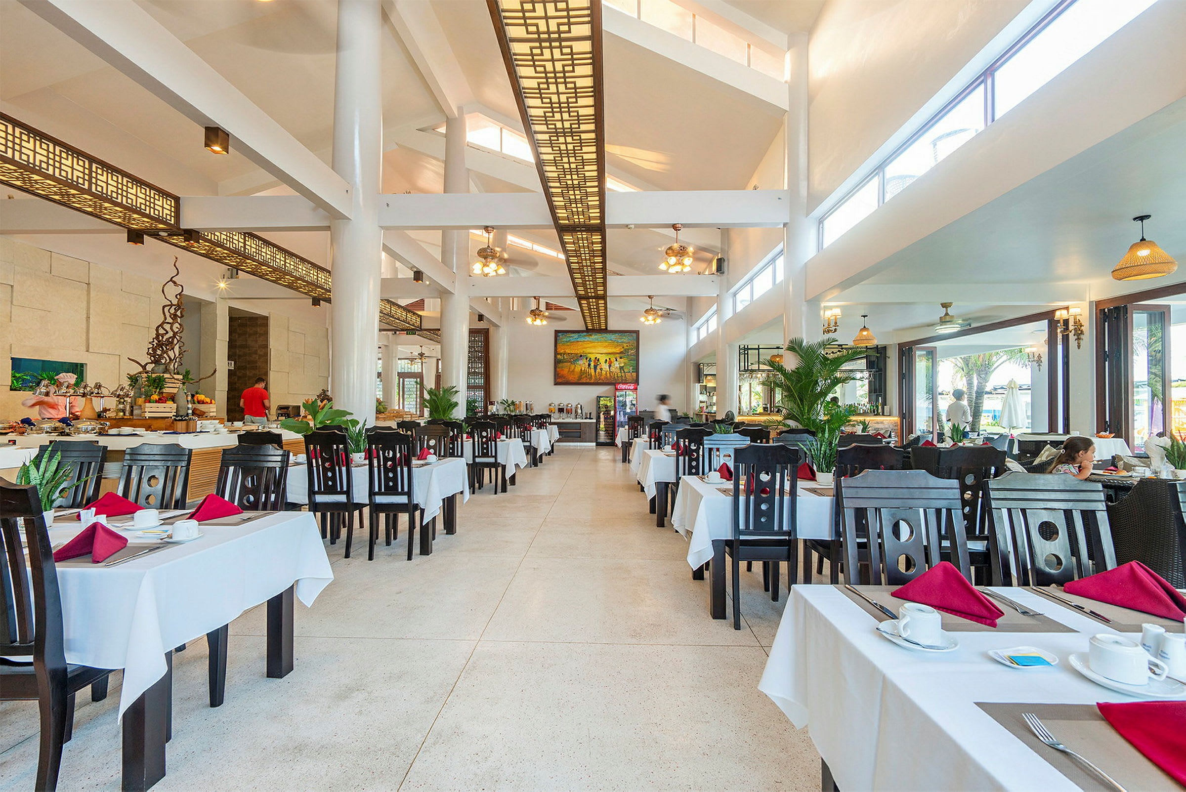 En rymlig restaurang med många bord klädda med vita dukar. (AI-genererad text)