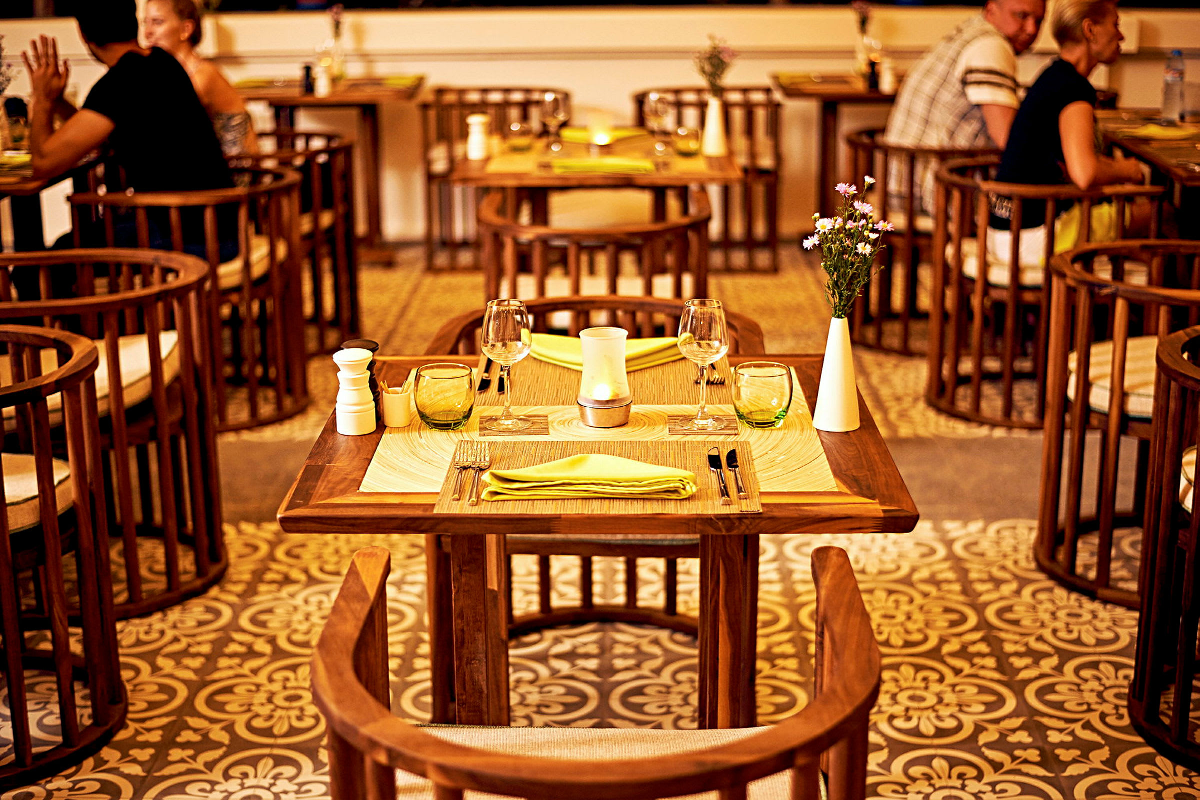 Ett dukat bord med dekorationer står i ett restaurangområde, omgiven av stolar och fler bord. (AI-genererad text)