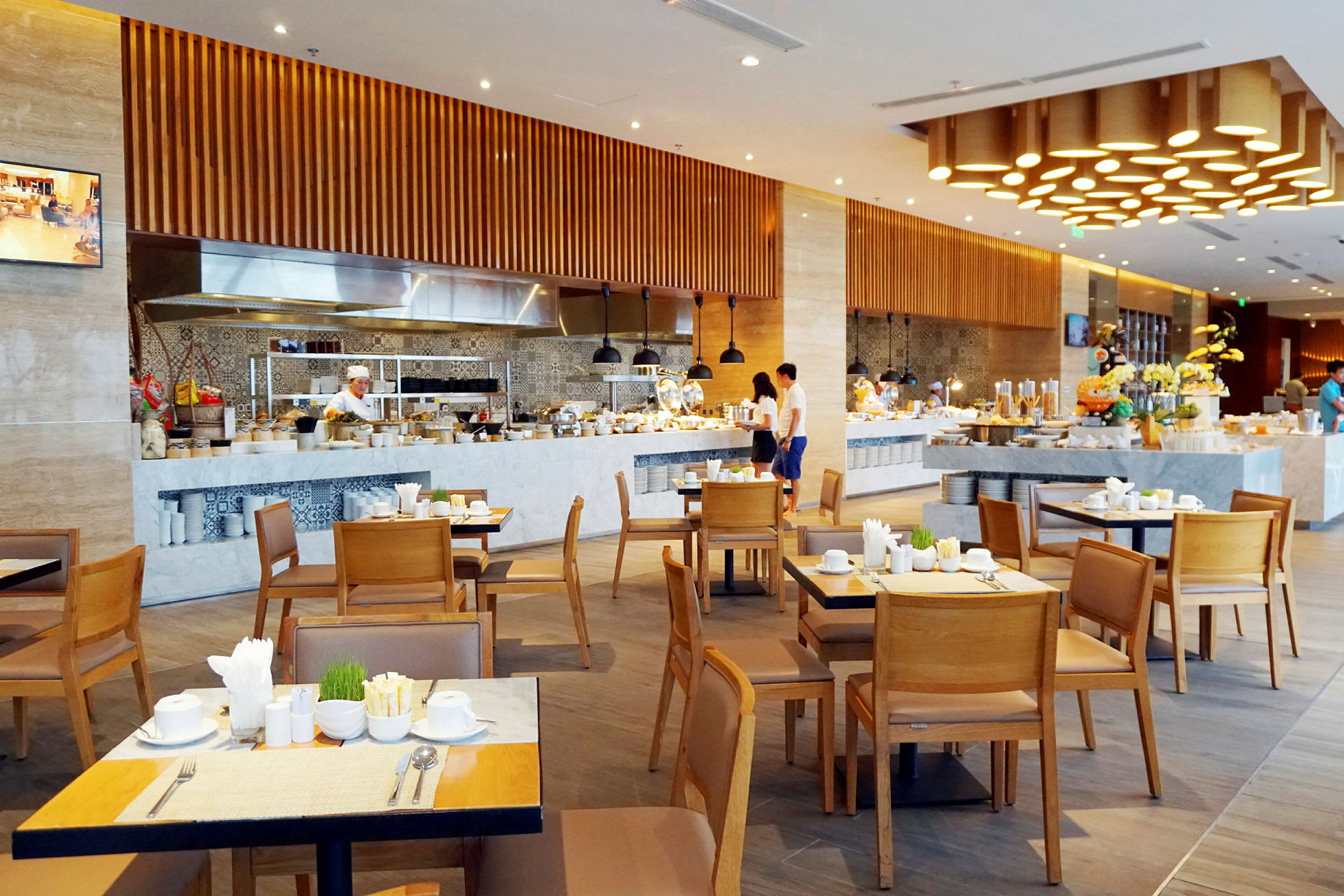 En restaurang med dukade bord, köksutrustning och personal som förbereder måltider. (AI-genererad text)