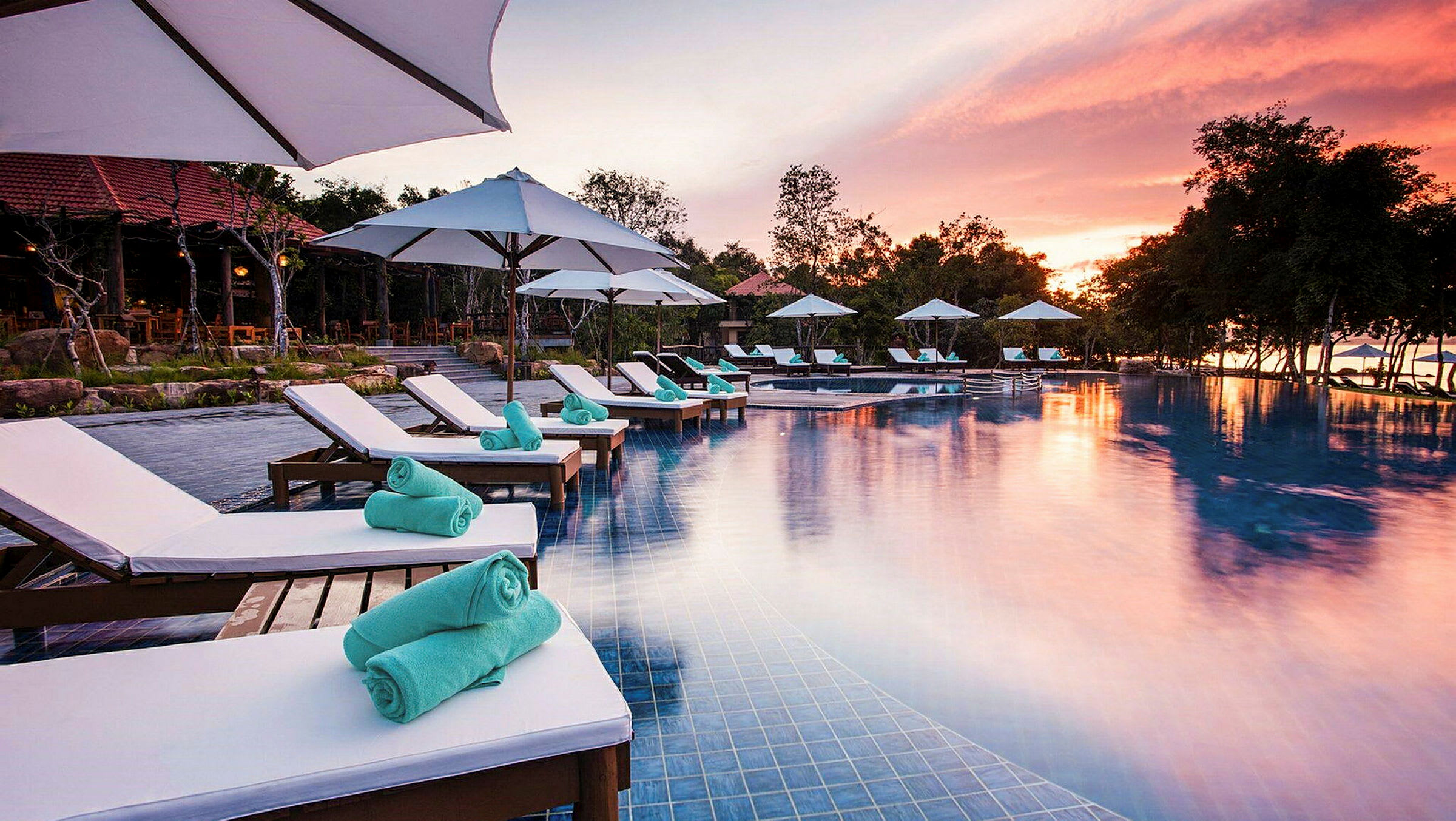 En infinitypool vid solnedgång med vita solstolar och parasoller runt om. (AI-genererad text)