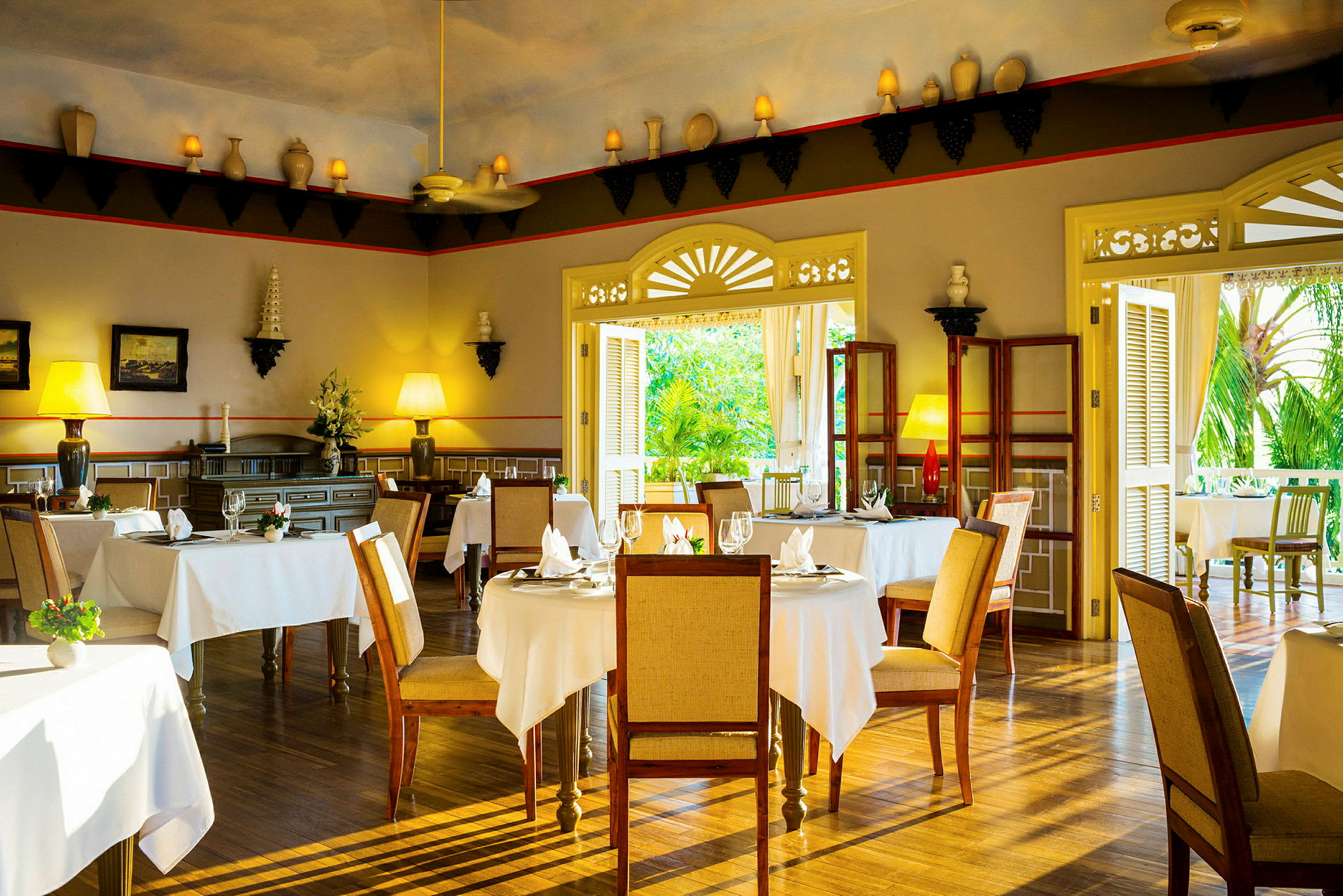 Interiör av en elegant restaurang med bord täckta med vita dukar, trästolar och dekorativa element på väggarna. (AI-genererad text)