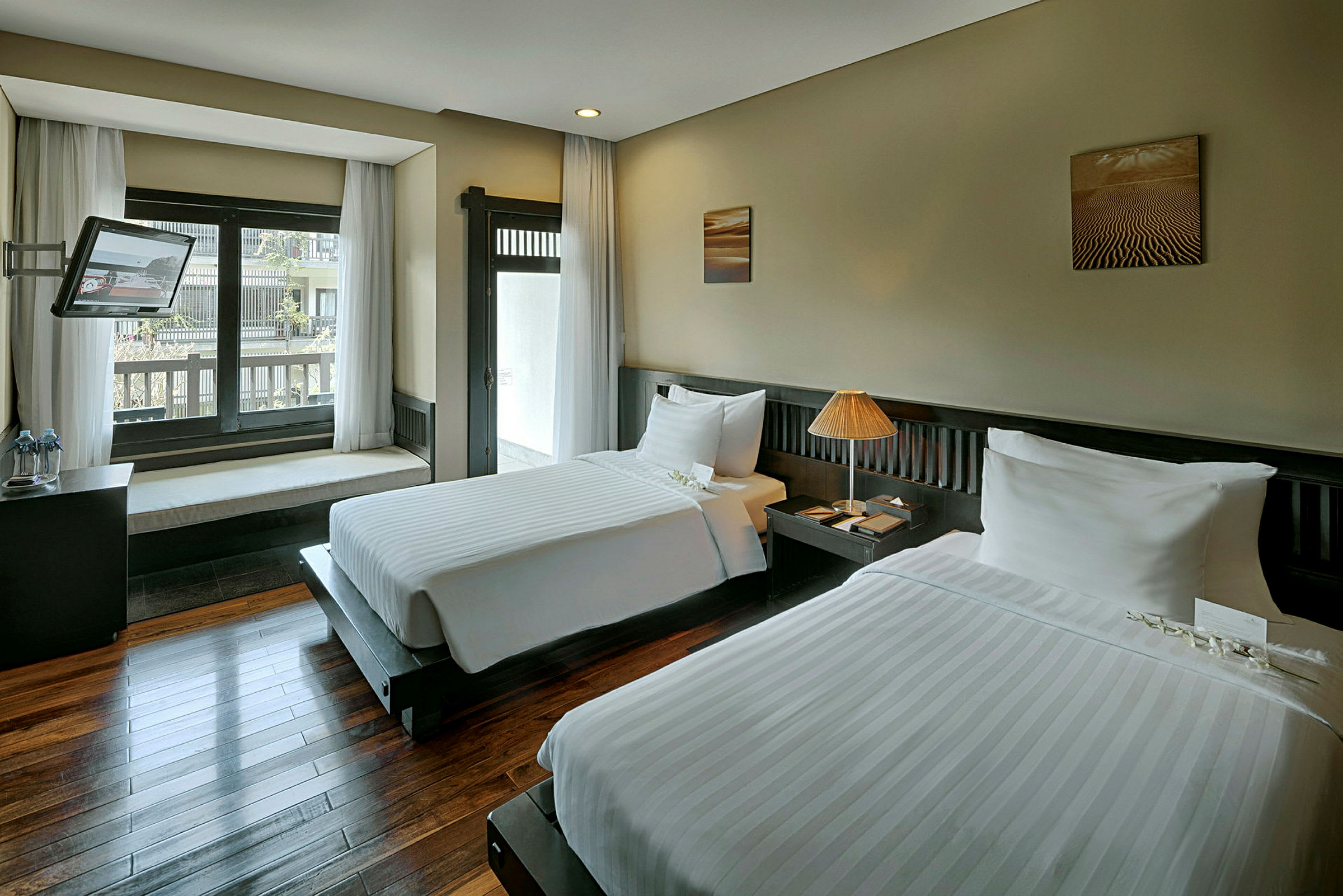 Ett hotellrum med två enkelsängar, en fönstersits och en TV. (AI-genererad text)