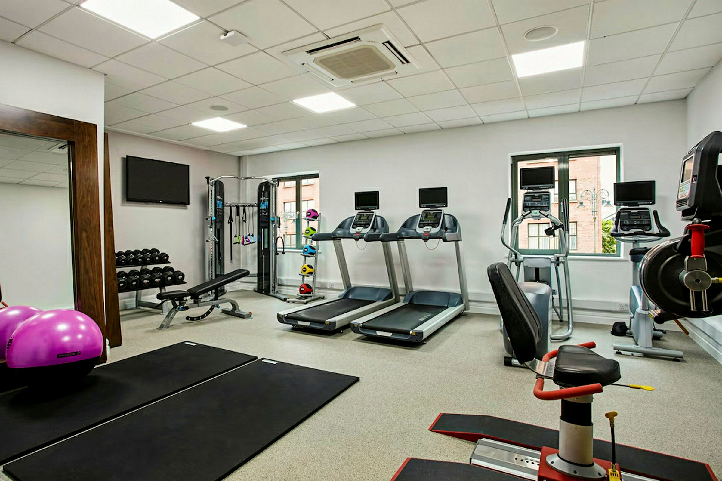Ett gym med löpband, träningsmaskiner, vikter och träningsmattor. (AI-genererad text)