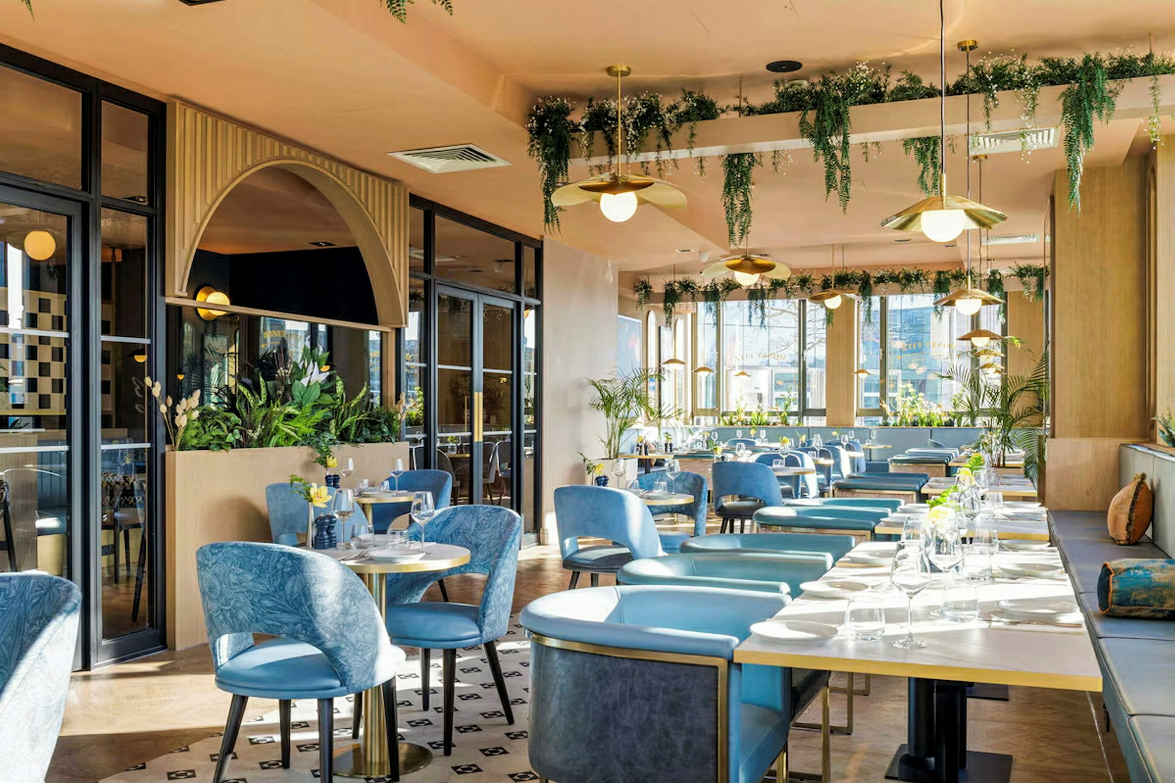 En restaurang med blå stolar, bord och växtdekorationer. (AI-genererad text)