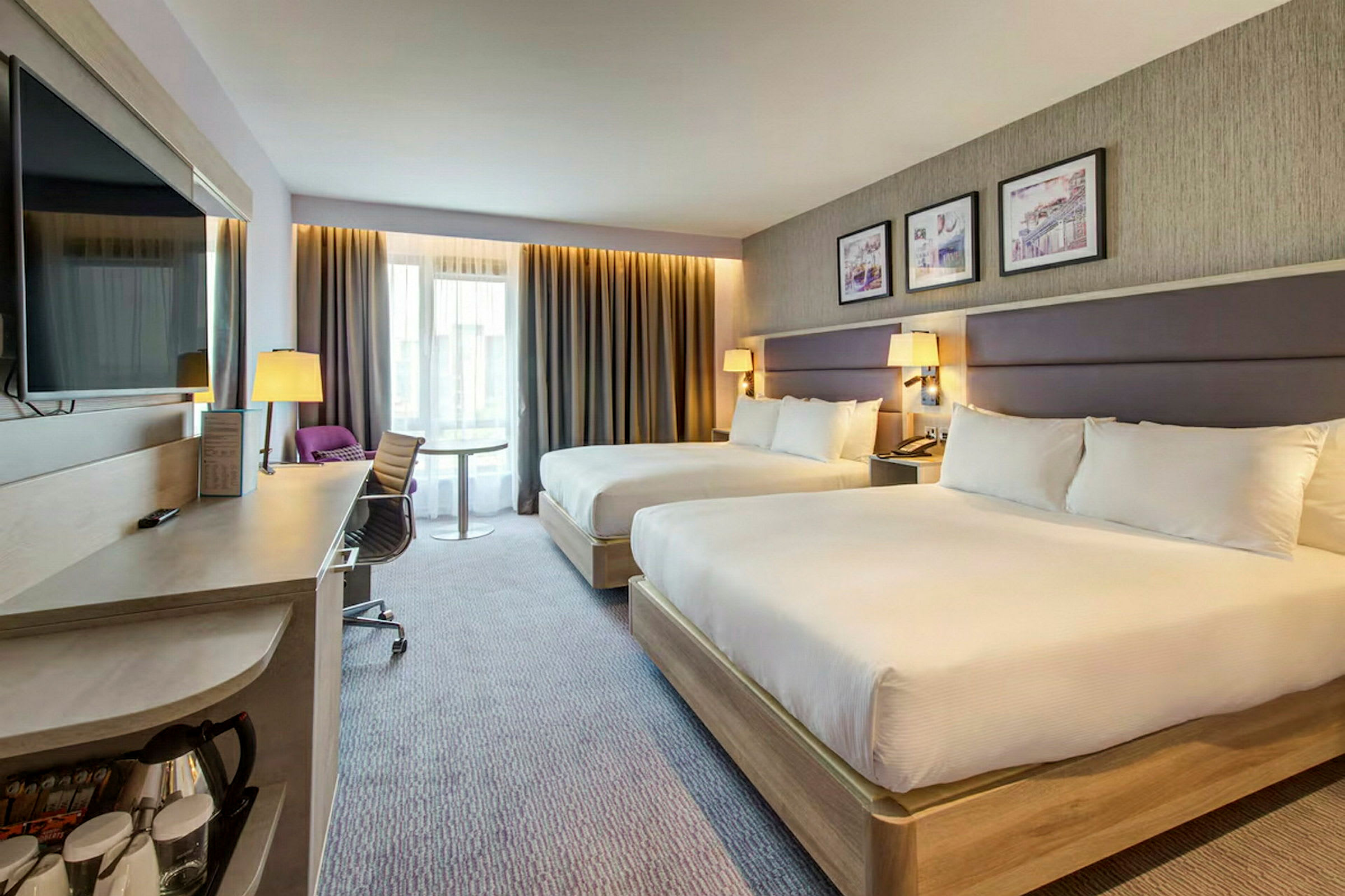 Hotellrum med två breda sängar, skrivbord och modern inredning. (AI-genererad text)