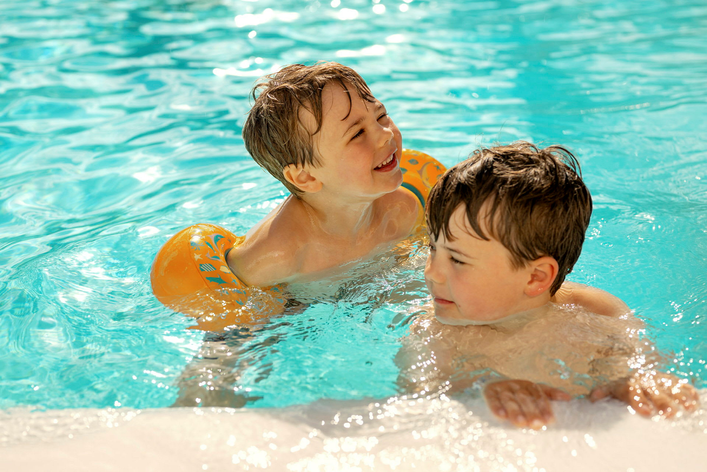 Två barn leker i en swimmingpool fylld med klart vatten. (AI-genererad text)