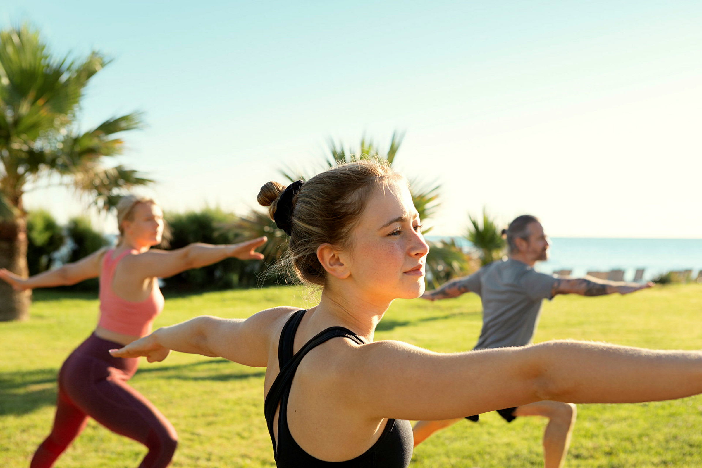 Personer som utför yoga i en grön park med havet i bakgrunden. (AI-genererad text)