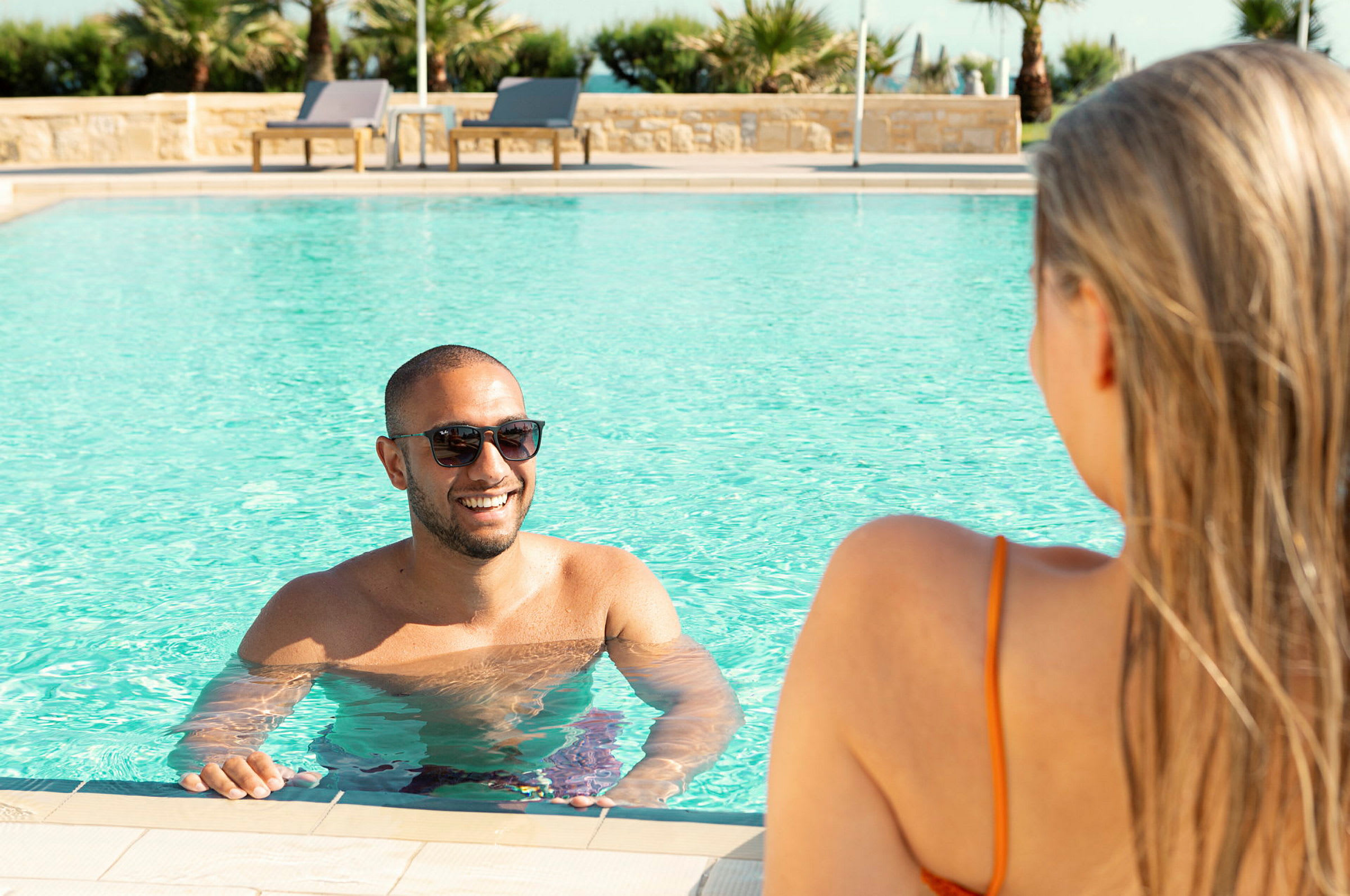 Person badar i pool med palmer i bakgrunden. (AI-genererad text)