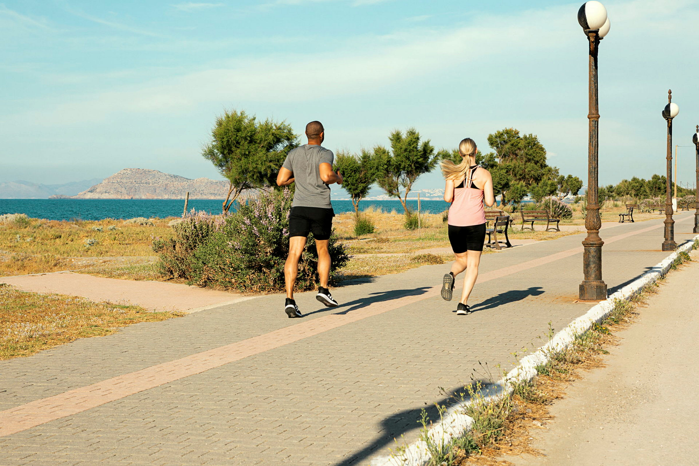 Två personer joggar på en gångväg vid havet. (AI-genererad text)
