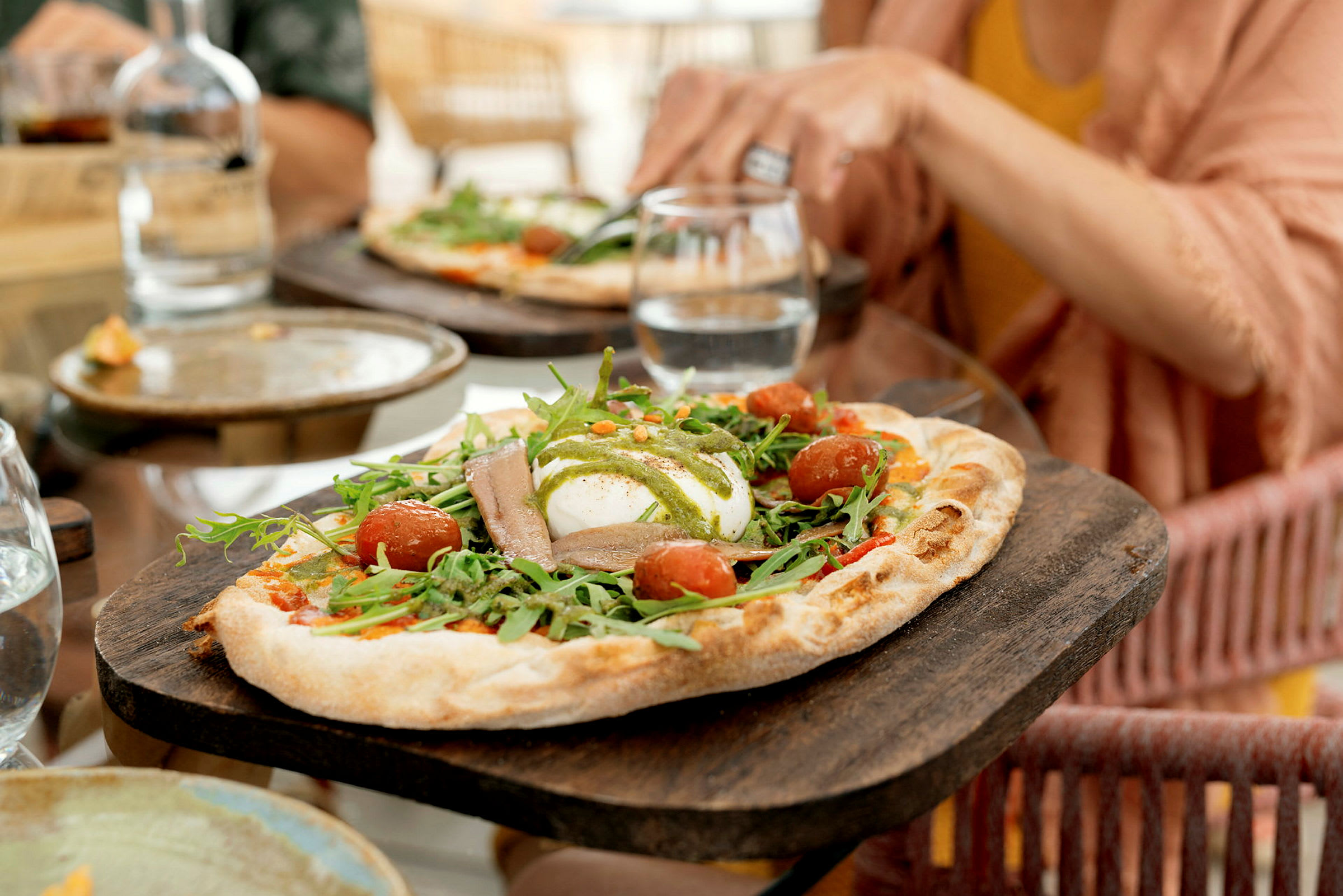 En närbild av en pizza med ruccola, körsbärstomater och mozzarella. (AI-genererad text)