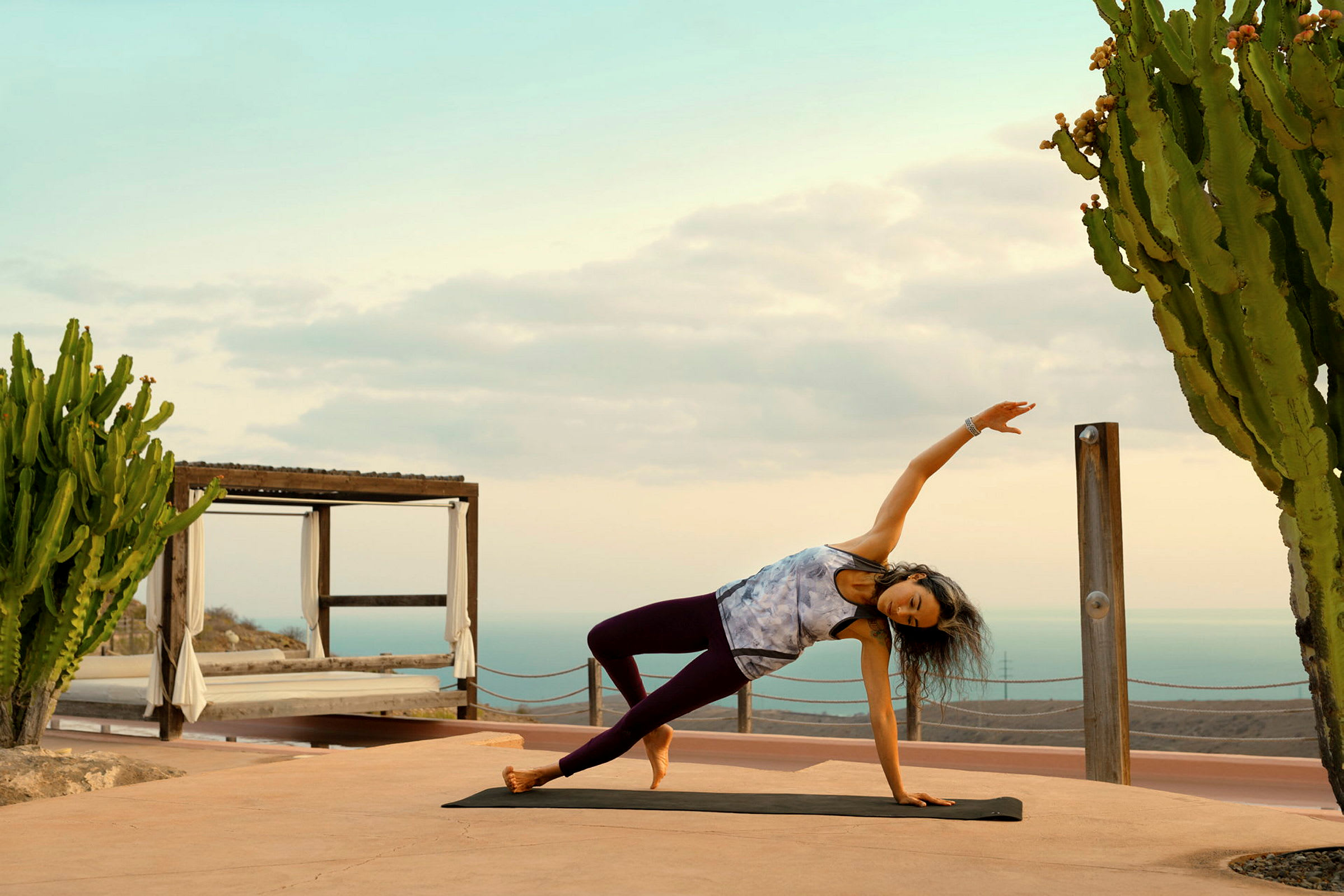 Person gör yoga på en matta utomhus bredvid en kaktus. (AI-genererad text)