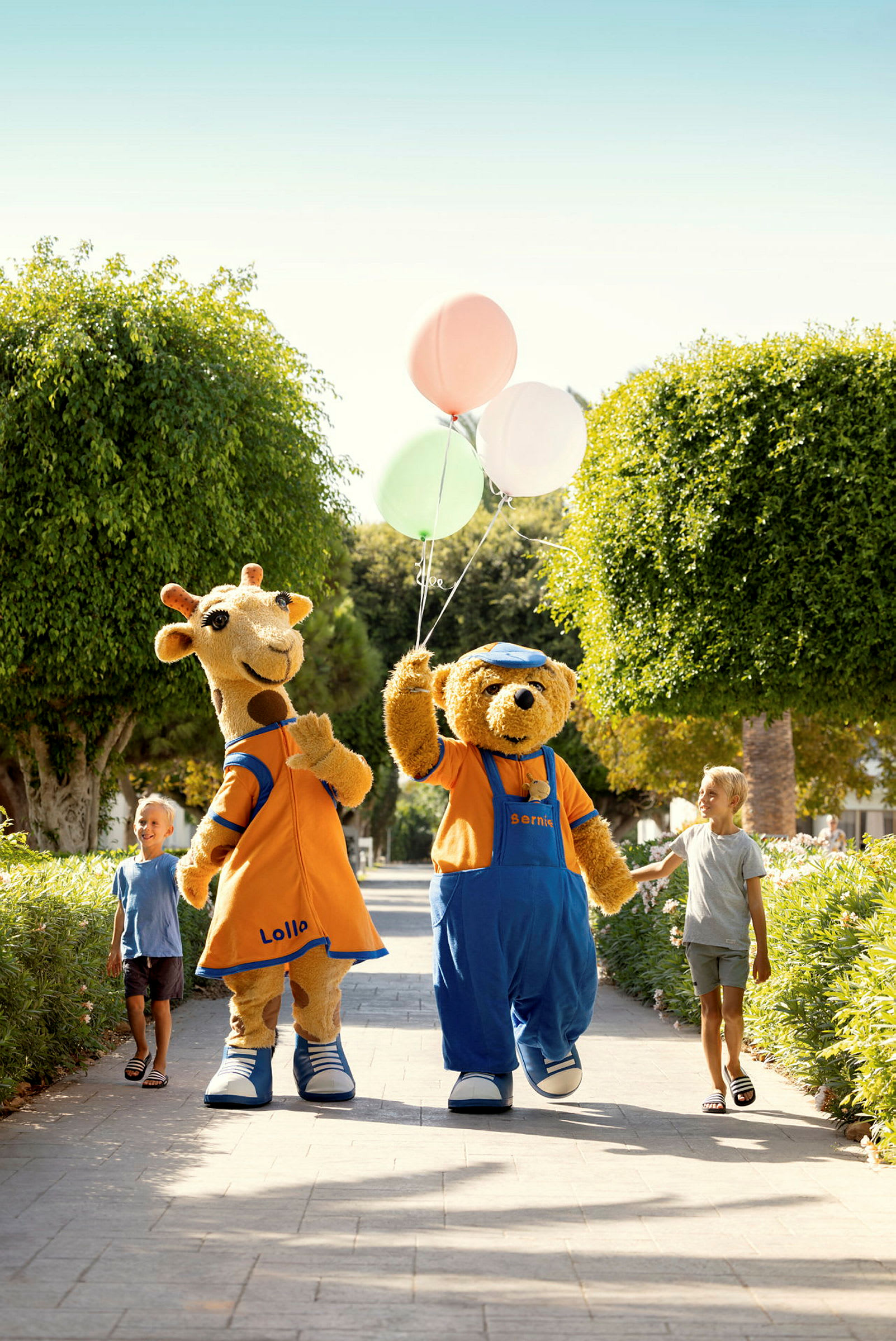 Två barn går tillsammans med två maskotar, en giraff och en björn, som bär på ballonger. (AI-genererad text)