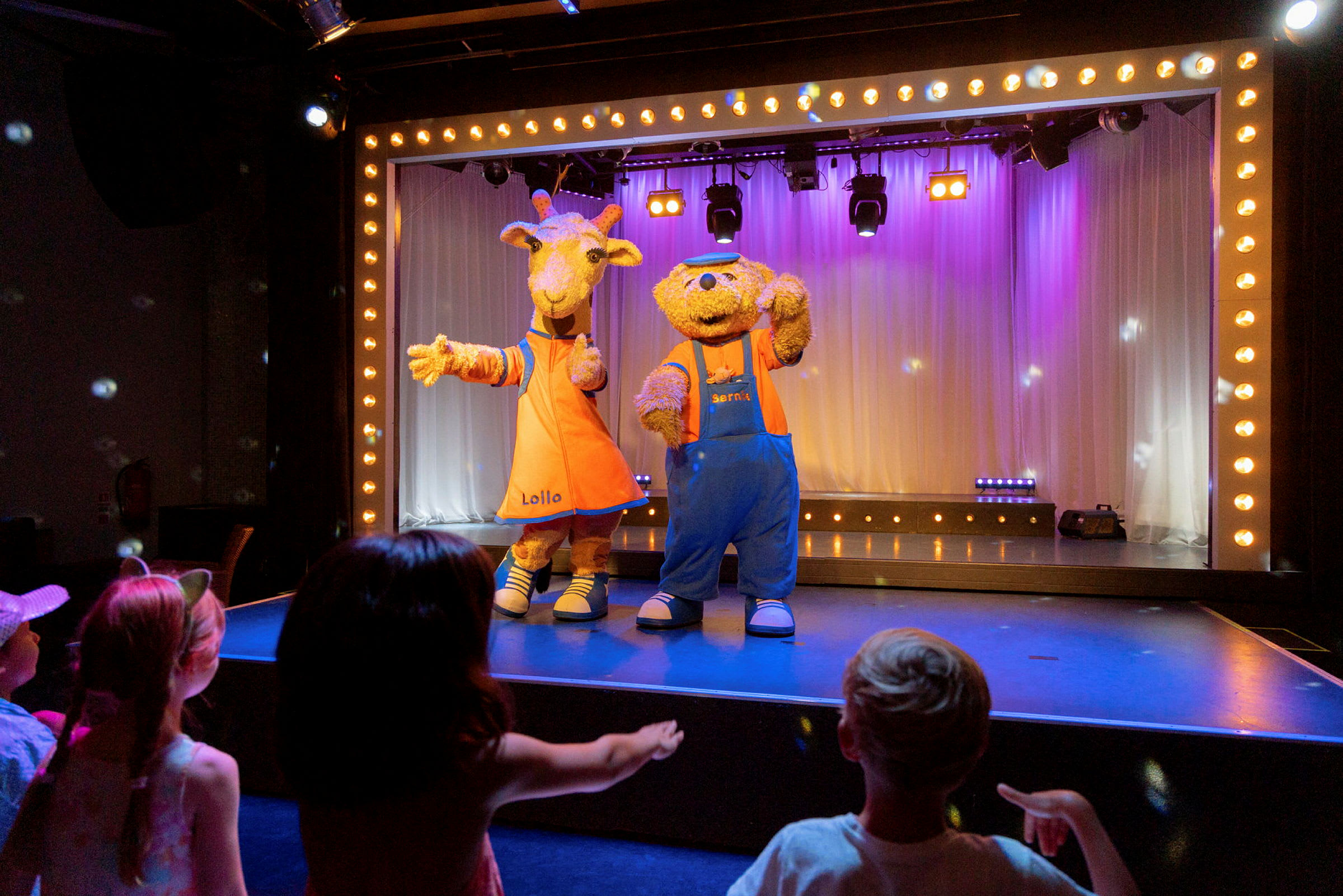 Två karaktärer, Lollo och Bernie, står på en scen och uppträder inför en publik av barn. (AI-genererad text)