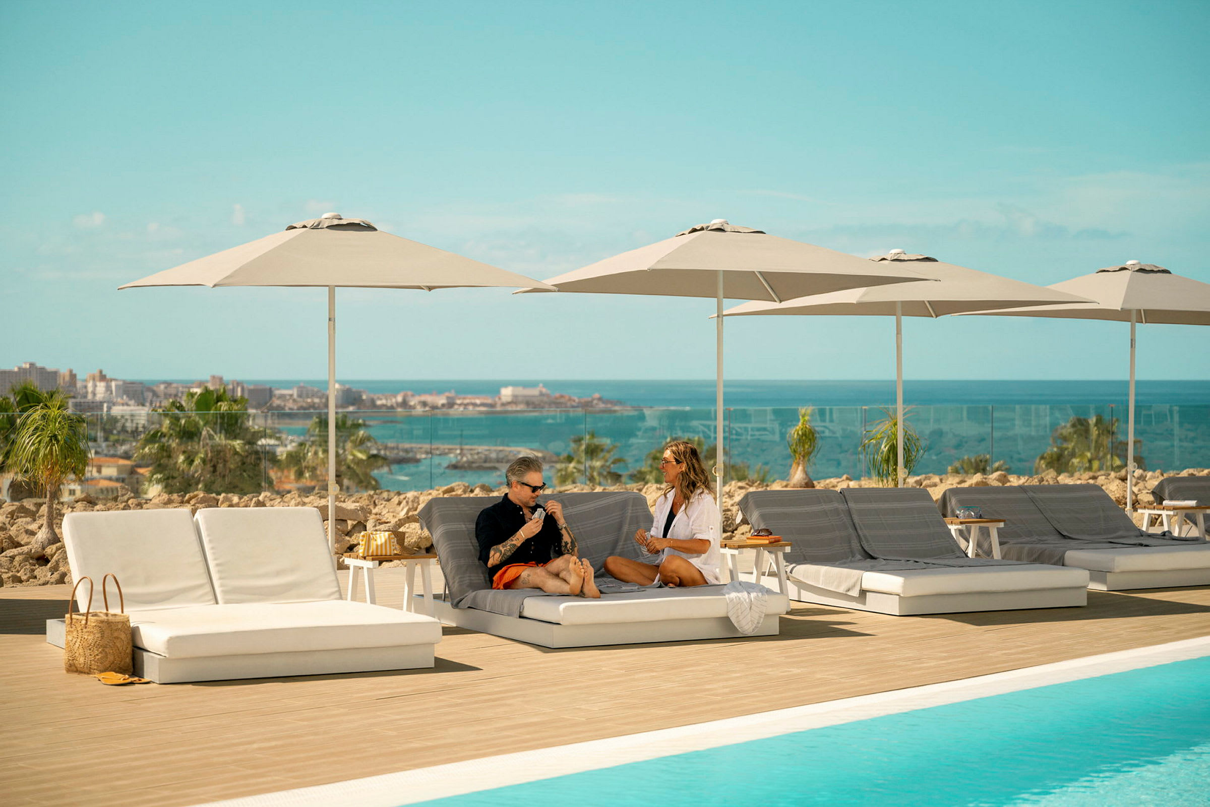 Solstolar och parasoller vid en pool med utsikt över havet. (AI-genererad text)