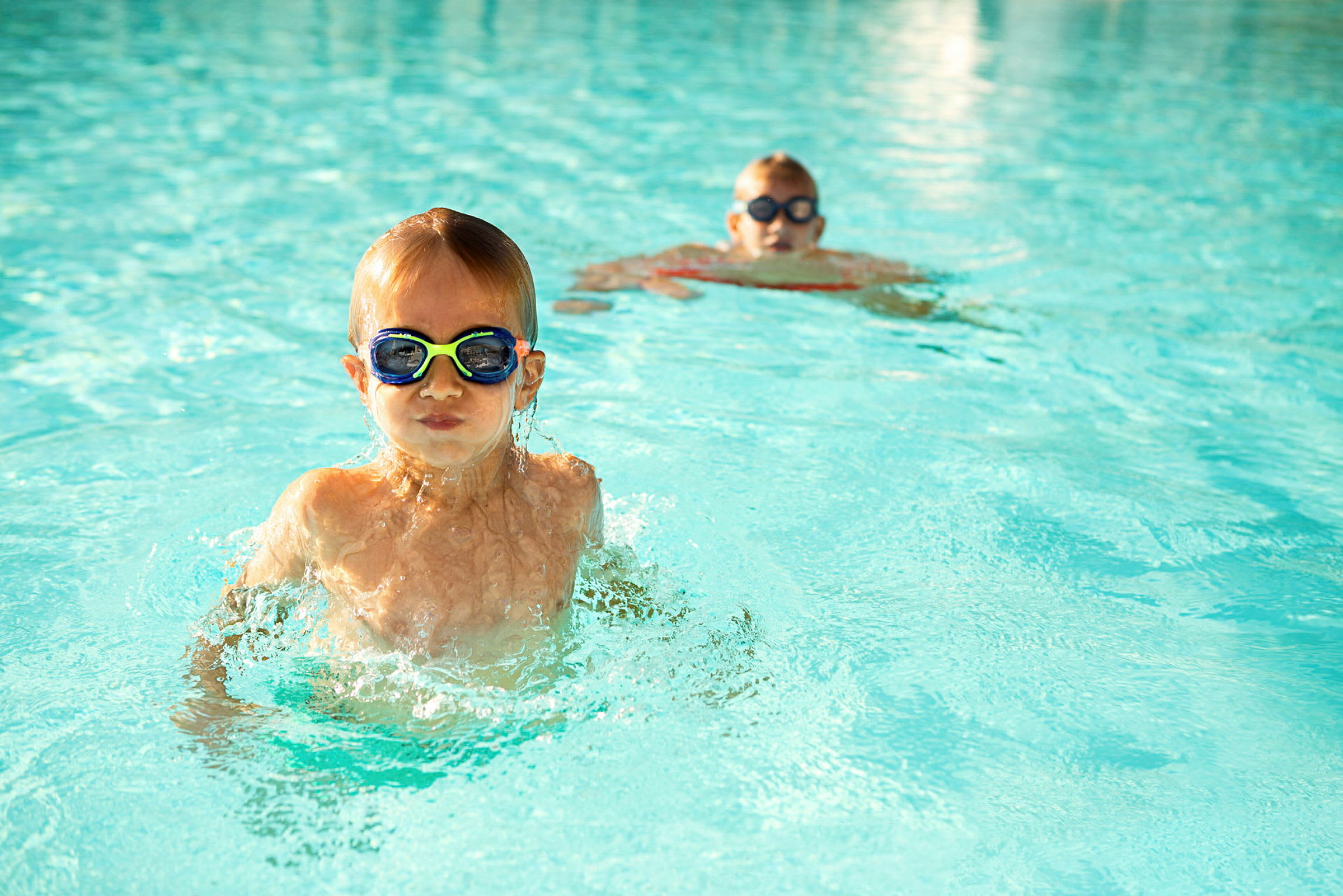 Två personer badar i en pool med klart vatten. (AI-genererad text)