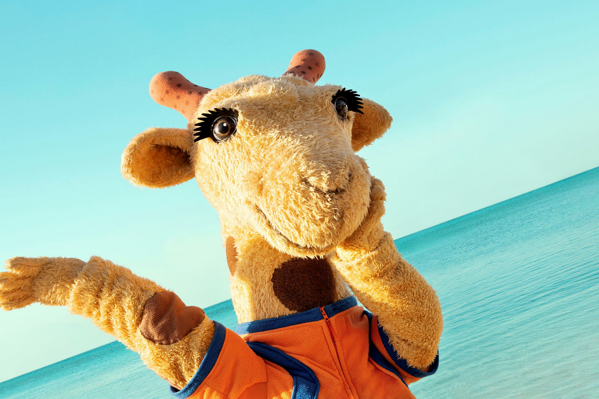 Maskot giraff vid stranden. (AI-genererad text)