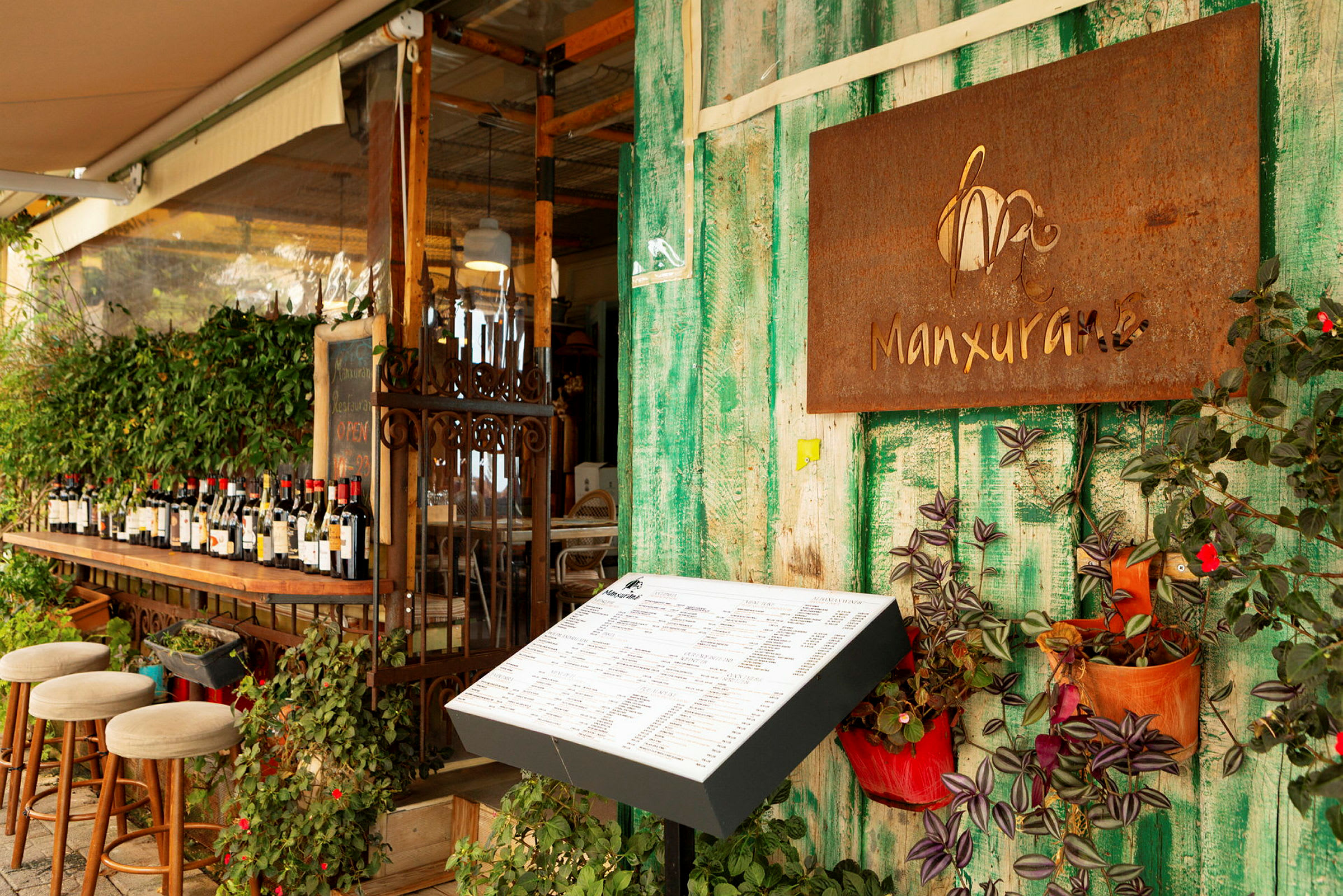 En öppen restaurang med gröna väggar, en meny på display och flaskor av vin på en bar. (AI-genererad text)
