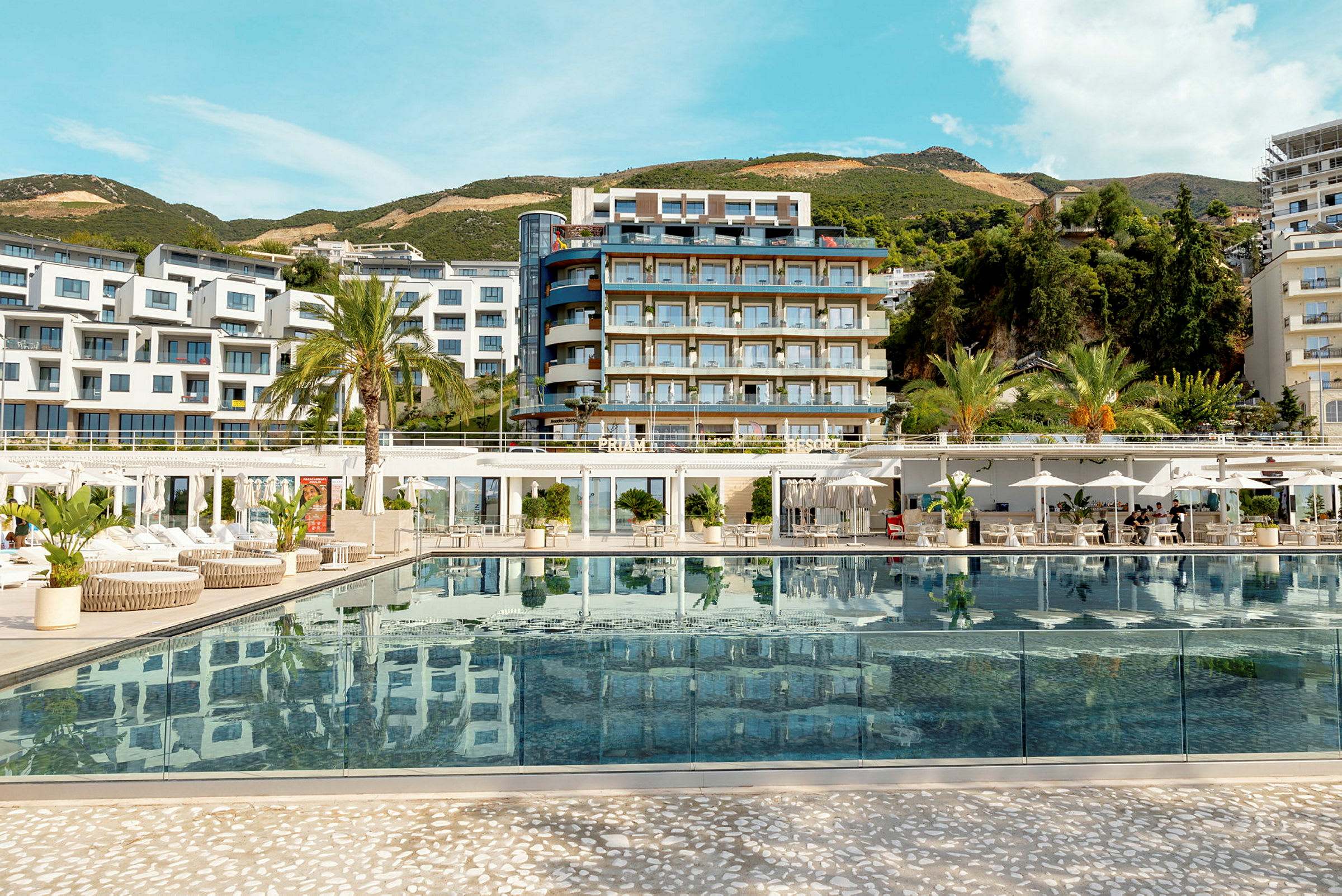 Lyxig resort med pool i förgrunden och moderna byggnader i bakgrunden. (AI-genererad text)