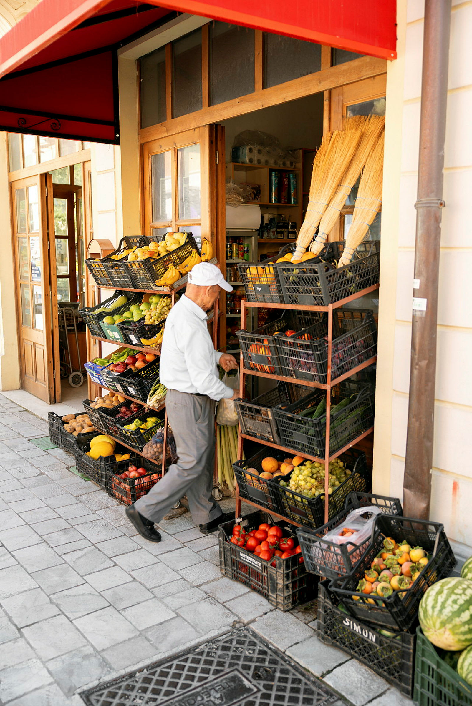 Äldre man plockar från grönsaksställ utanför en butik. (AI-genererad text)