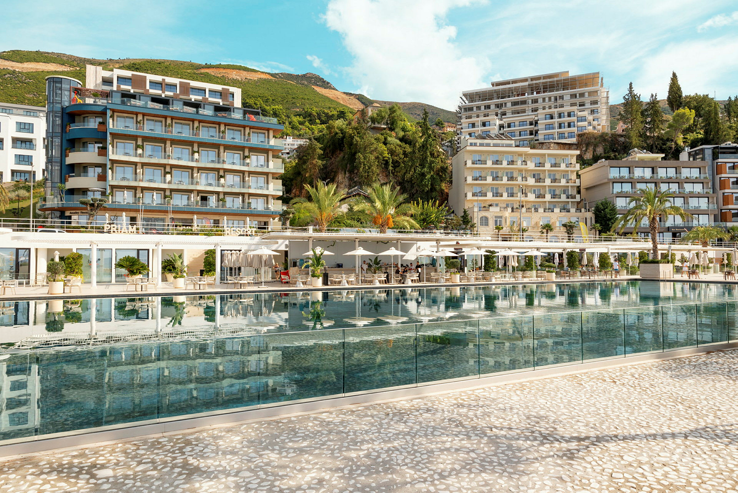 Hotellkomplex med pool i fokus, omgiven av grönska och byggnader. (AI-genererad text)