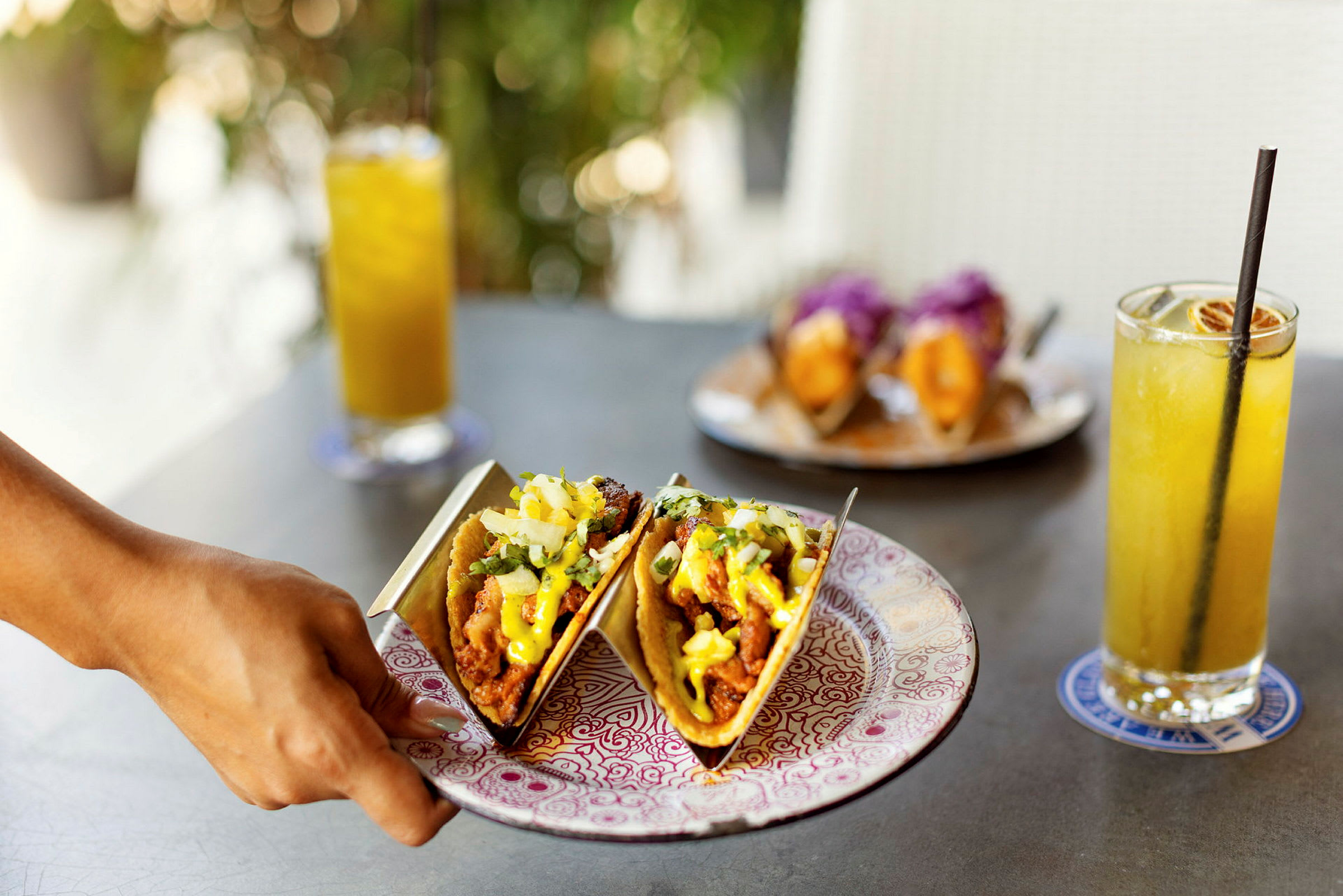 Två tacos på en tallrik med drycker i bakgrunden. (AI-genererad text)
