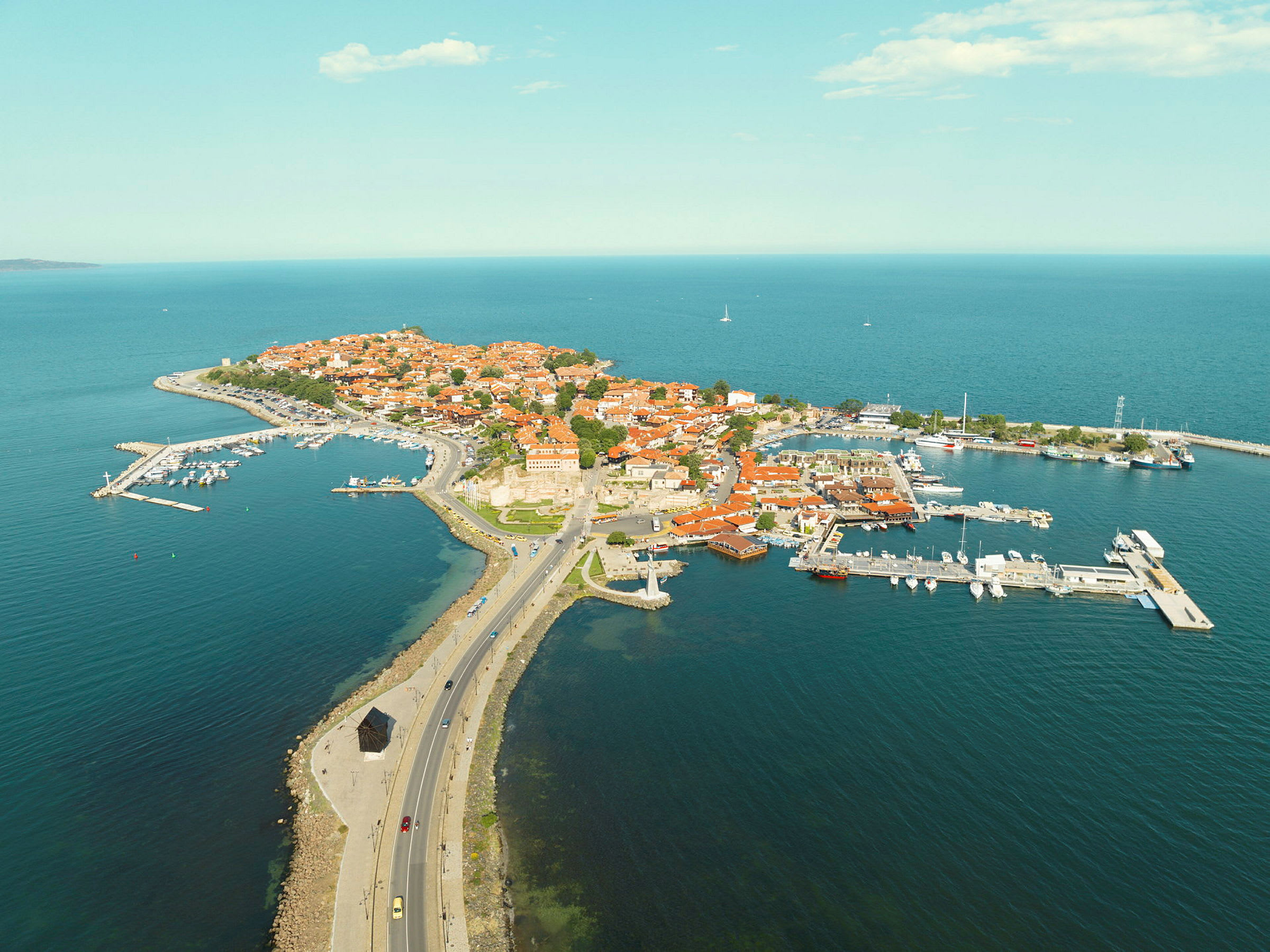 Flygfoto av en halvö med röda tak och hamn. (AI-genererad text)