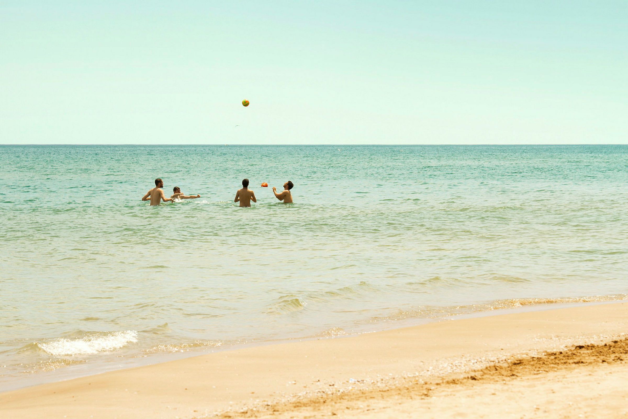 Personer som spelar med en boll i havet nära en sandstrand. (AI-genererad text)