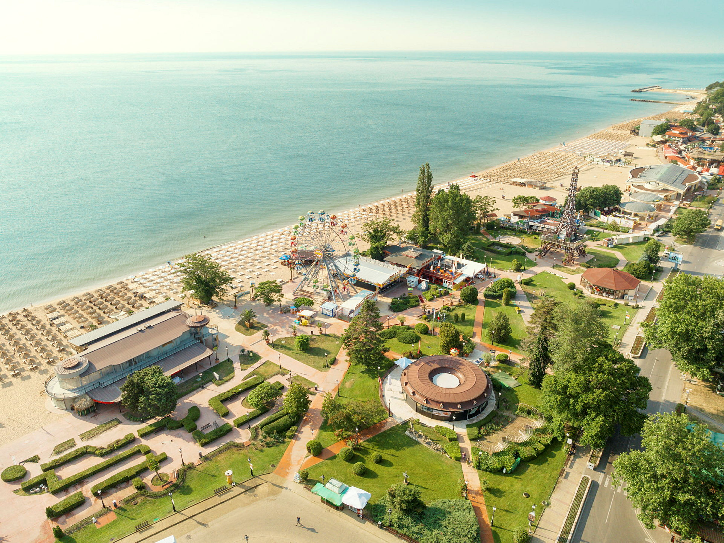 Strand med solstolar, nöjesparksområde och grönska. (AI-genererad text)