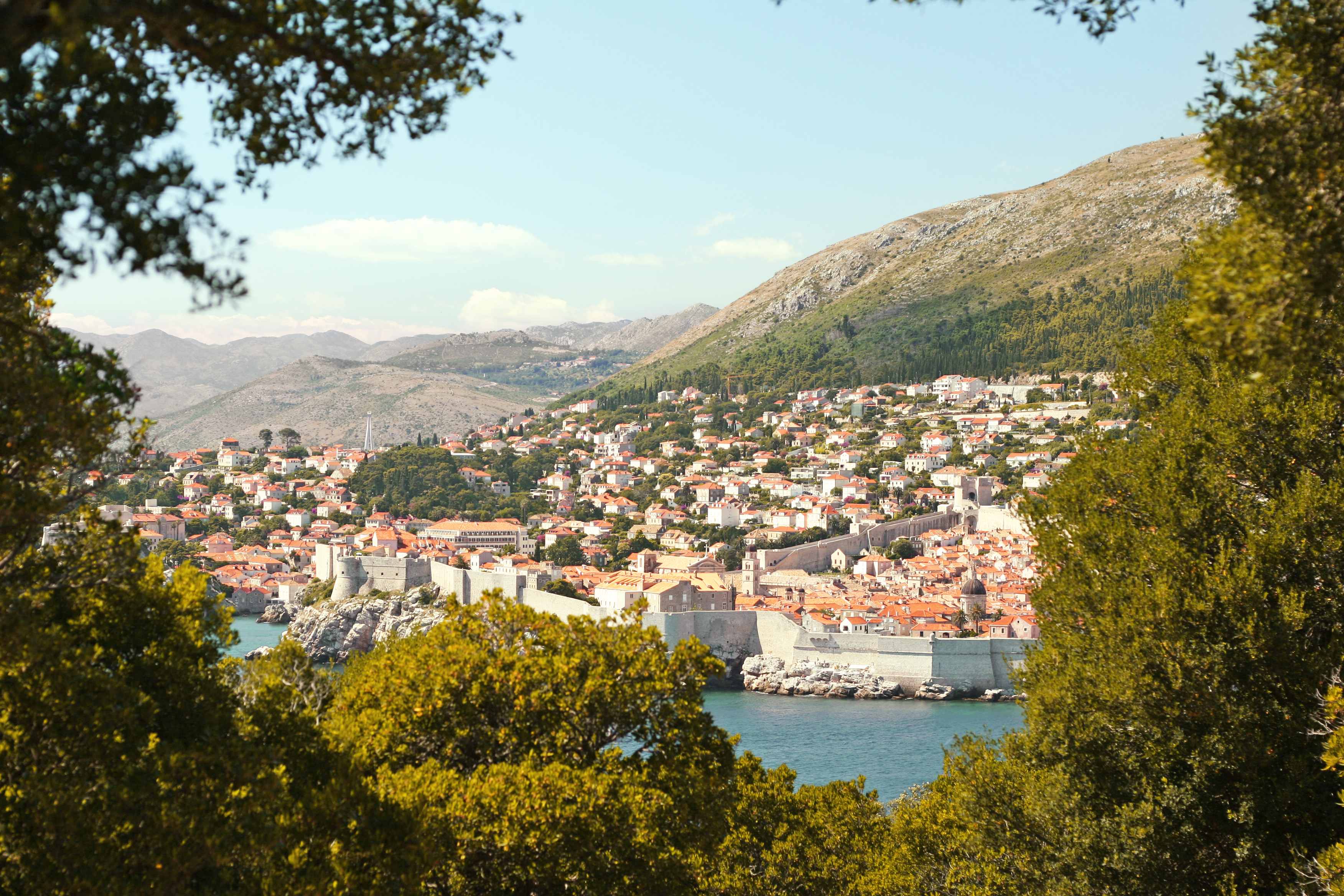 En vy över Dubrovnik med sin historiska stadsmur, omgiven av grönska. (AI-genererad text)