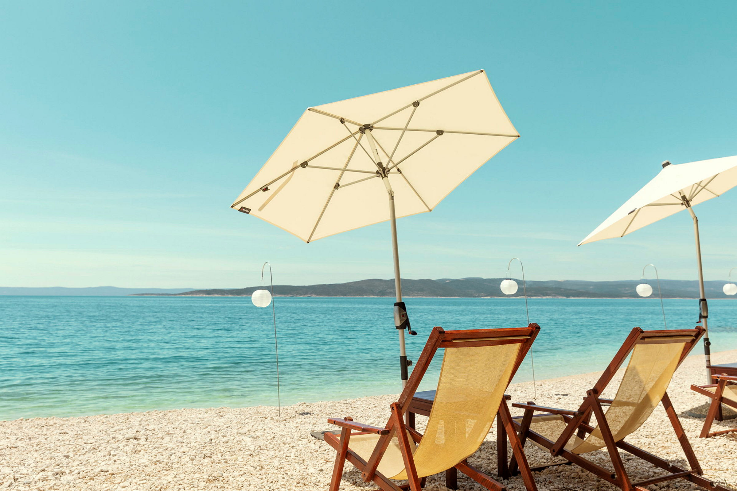 Solstolar och parasoller vid stranden med havet i bakgrunden. (AI-genererad text)