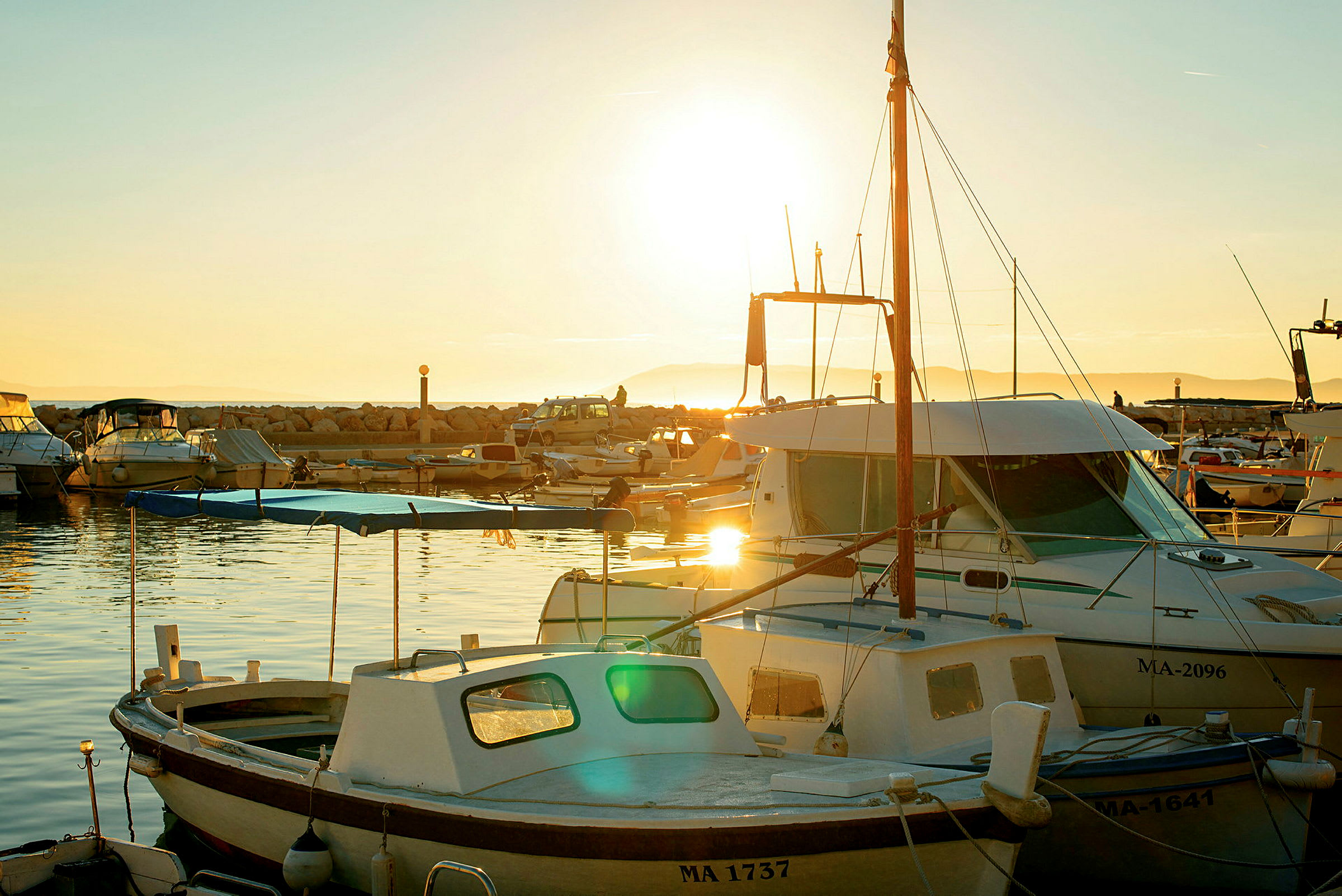En småbåtshamn med flera båtar belysta av solnedgångsljus. (AI-genererad text)