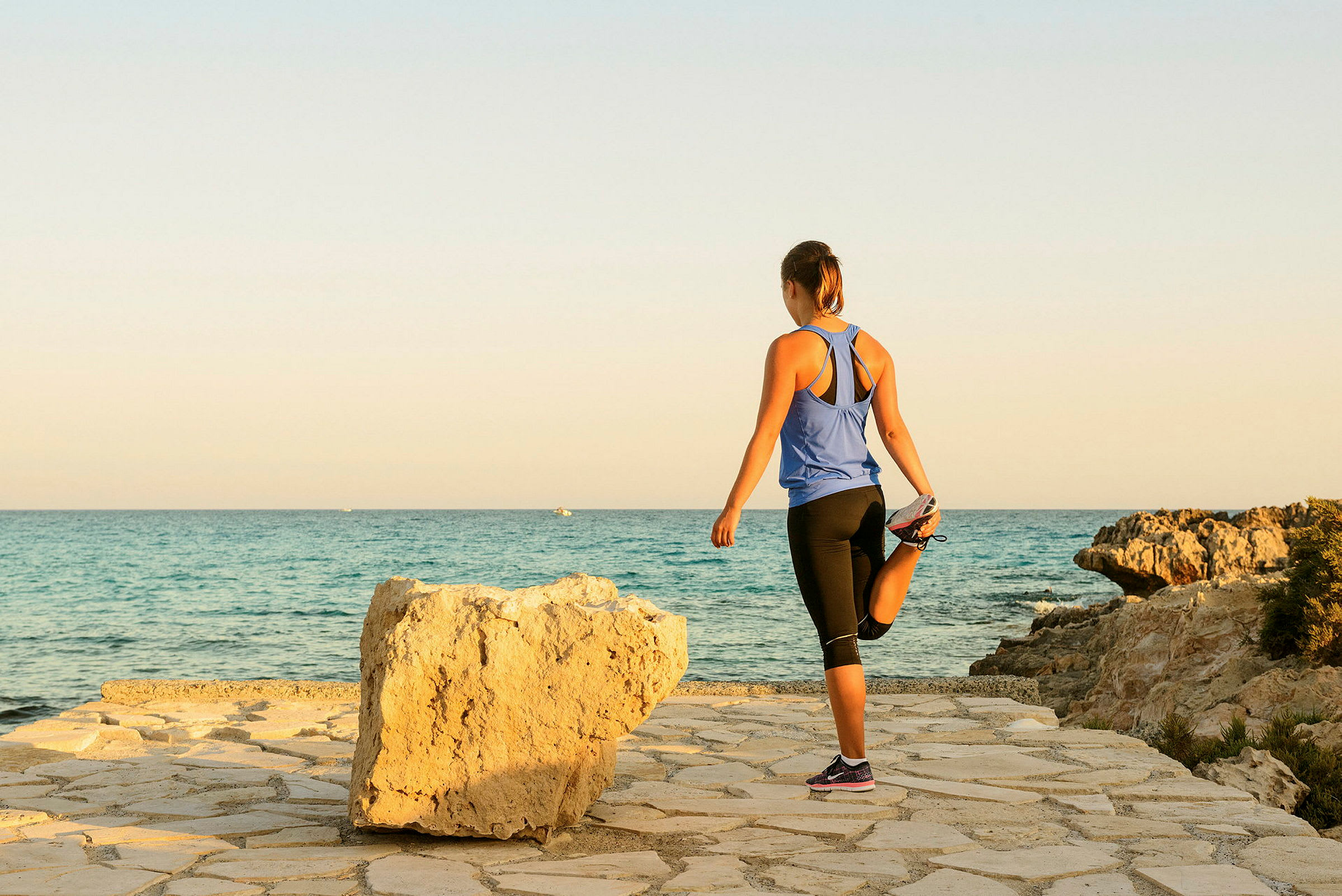 En person stretchar sitt ben vid havet. (AI-genererad text)
