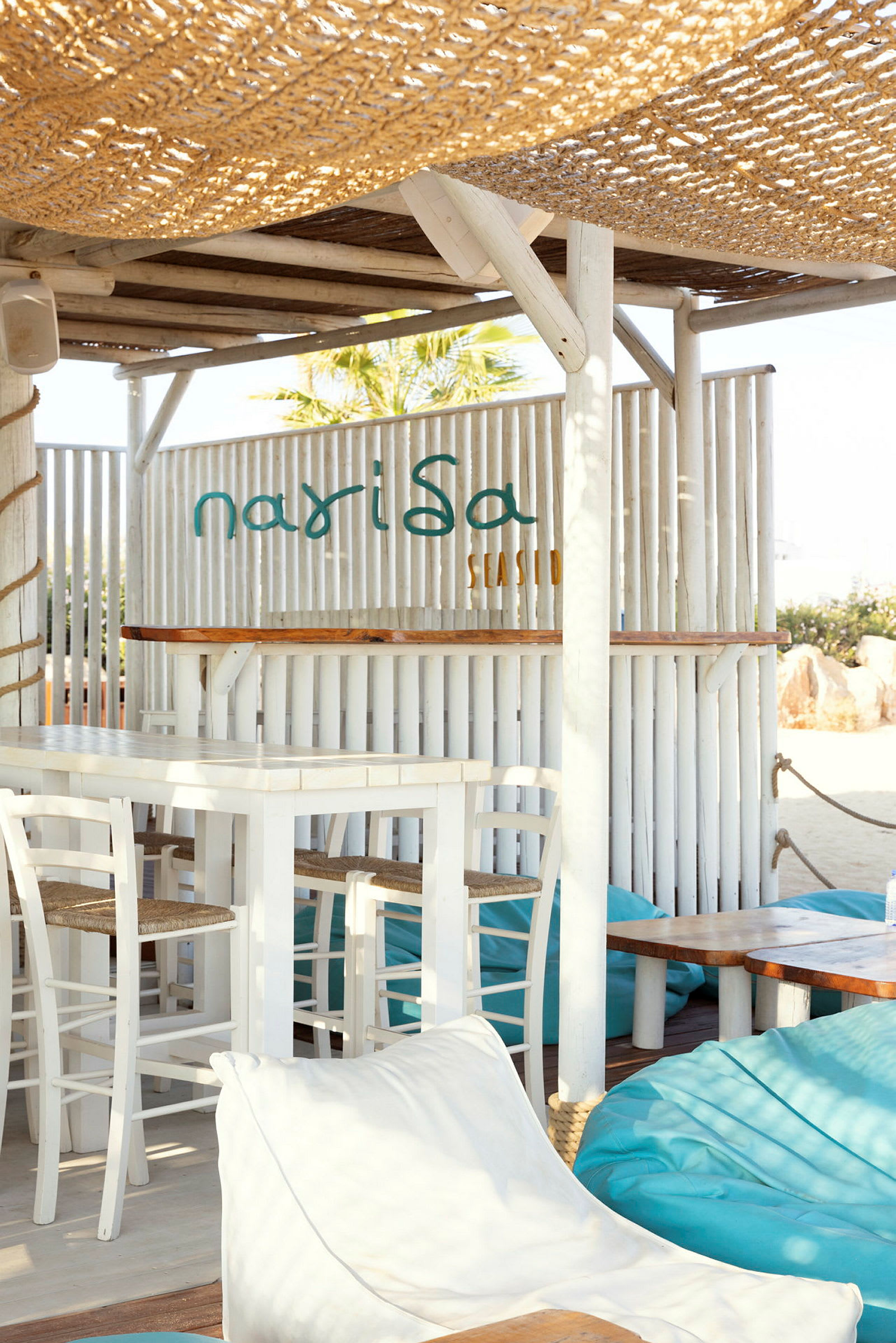 Plats med sittmöbler och skyddande tak, med varumärket Narisa Seaside. (AI-genererad text)