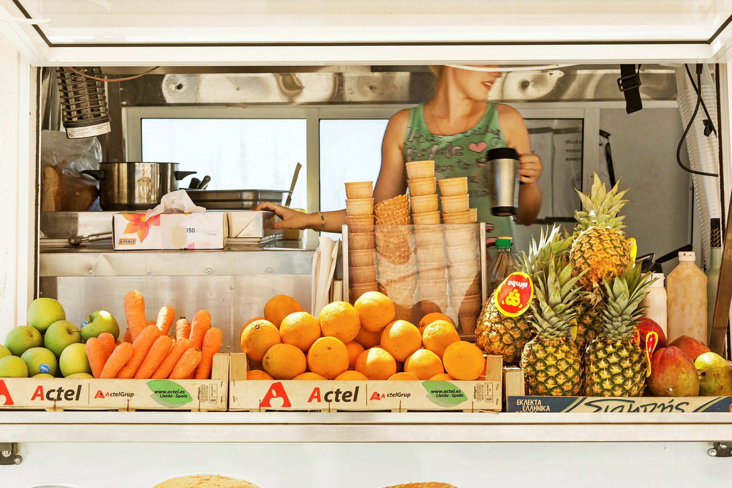 Ett marknadsstånd med frukter, inklusive morötter, apelsiner och ananas. (AI-genererad text)
