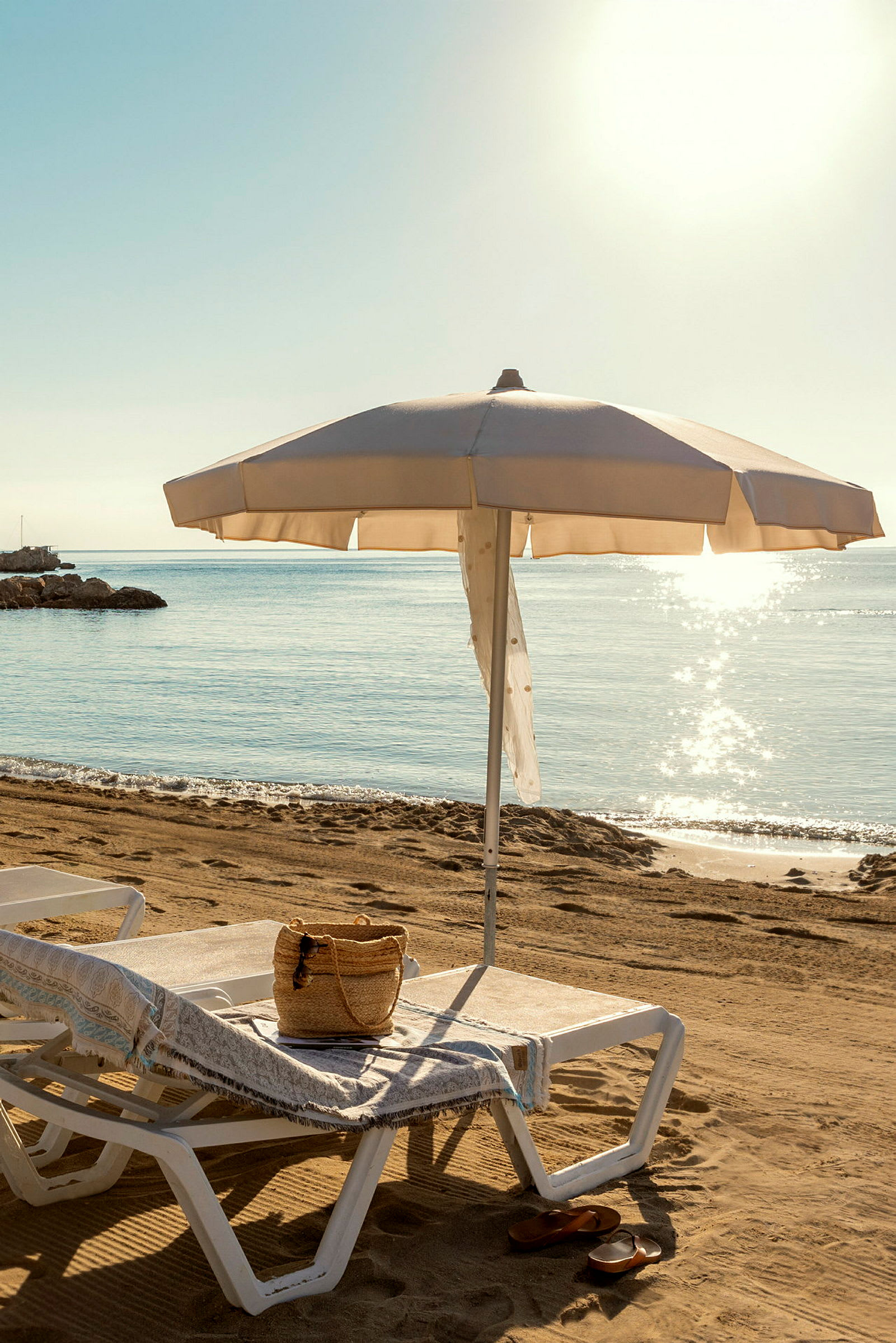 Strand med solstol och parasoll nära havet. (AI-genererad text)
