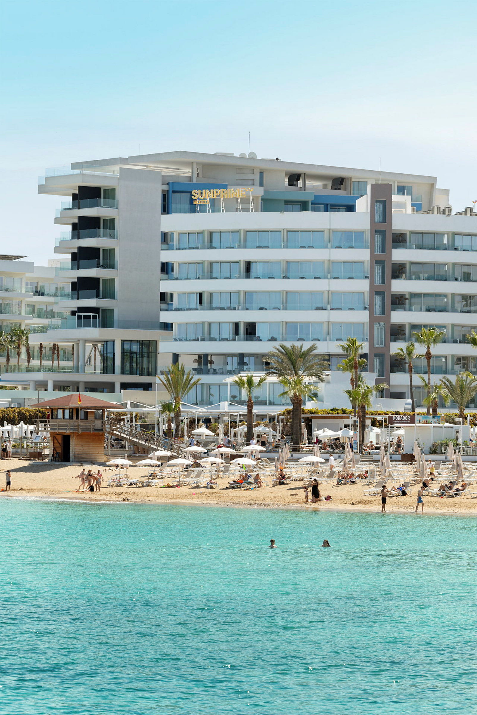 Ett strandhotell med solsängar och turkost hav i förgrunden. (AI-genererad text)