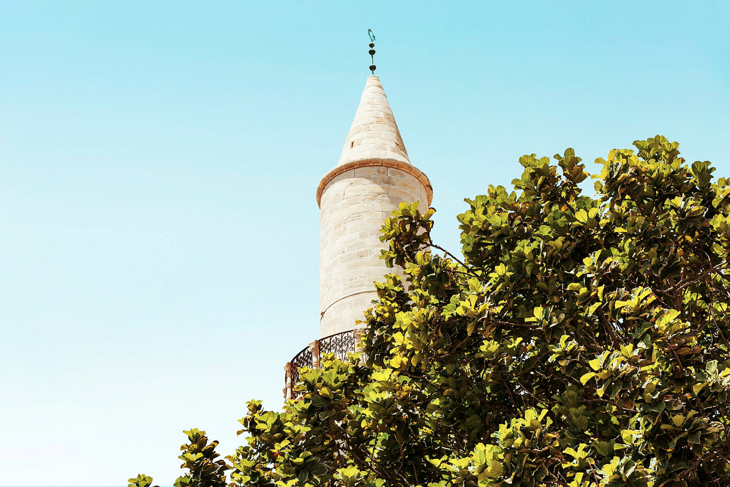 En minaret med träd i förgrunden. (AI-genererad text)