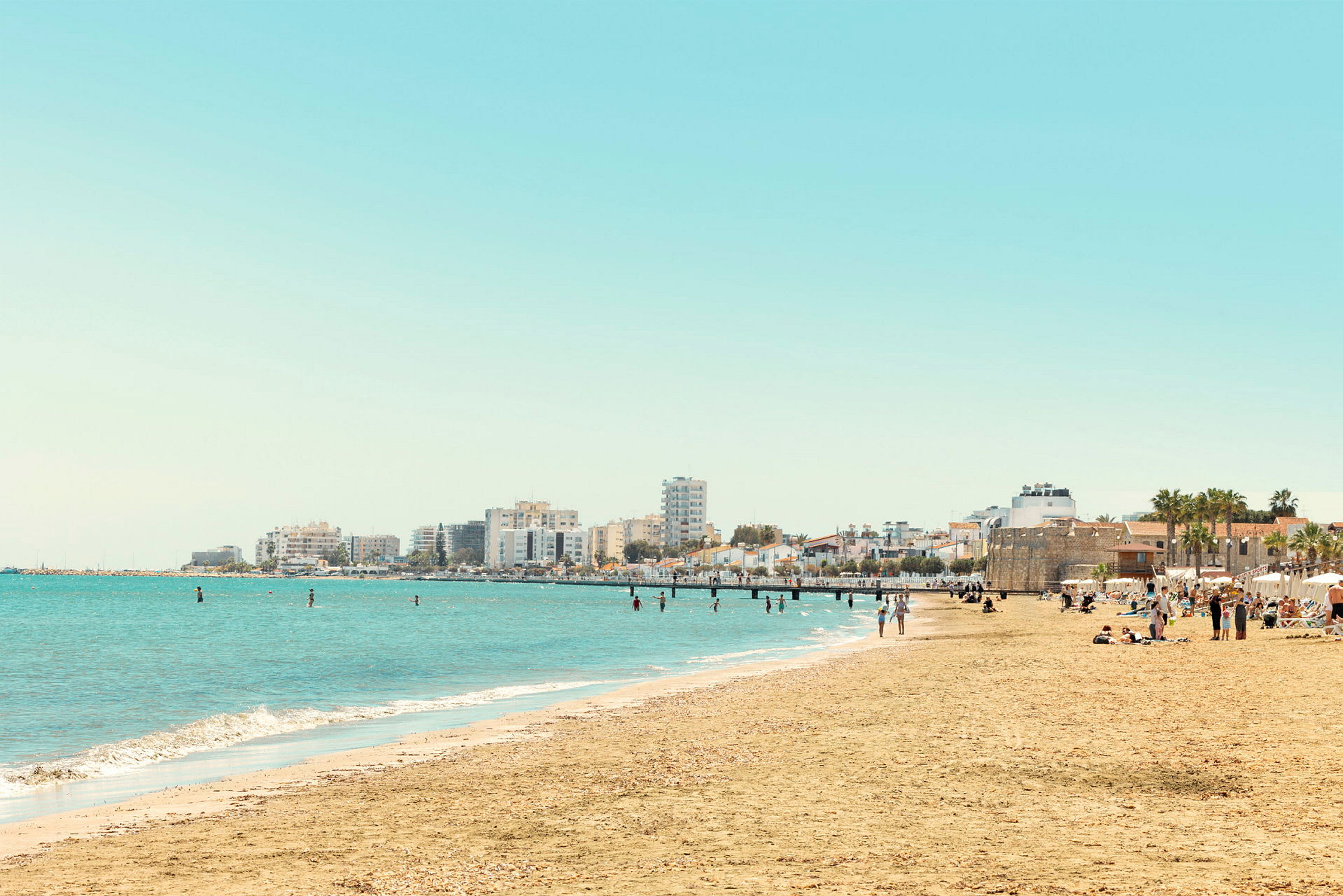 Strand med sand och byggnader i bakgrunden. (AI-genererad text)